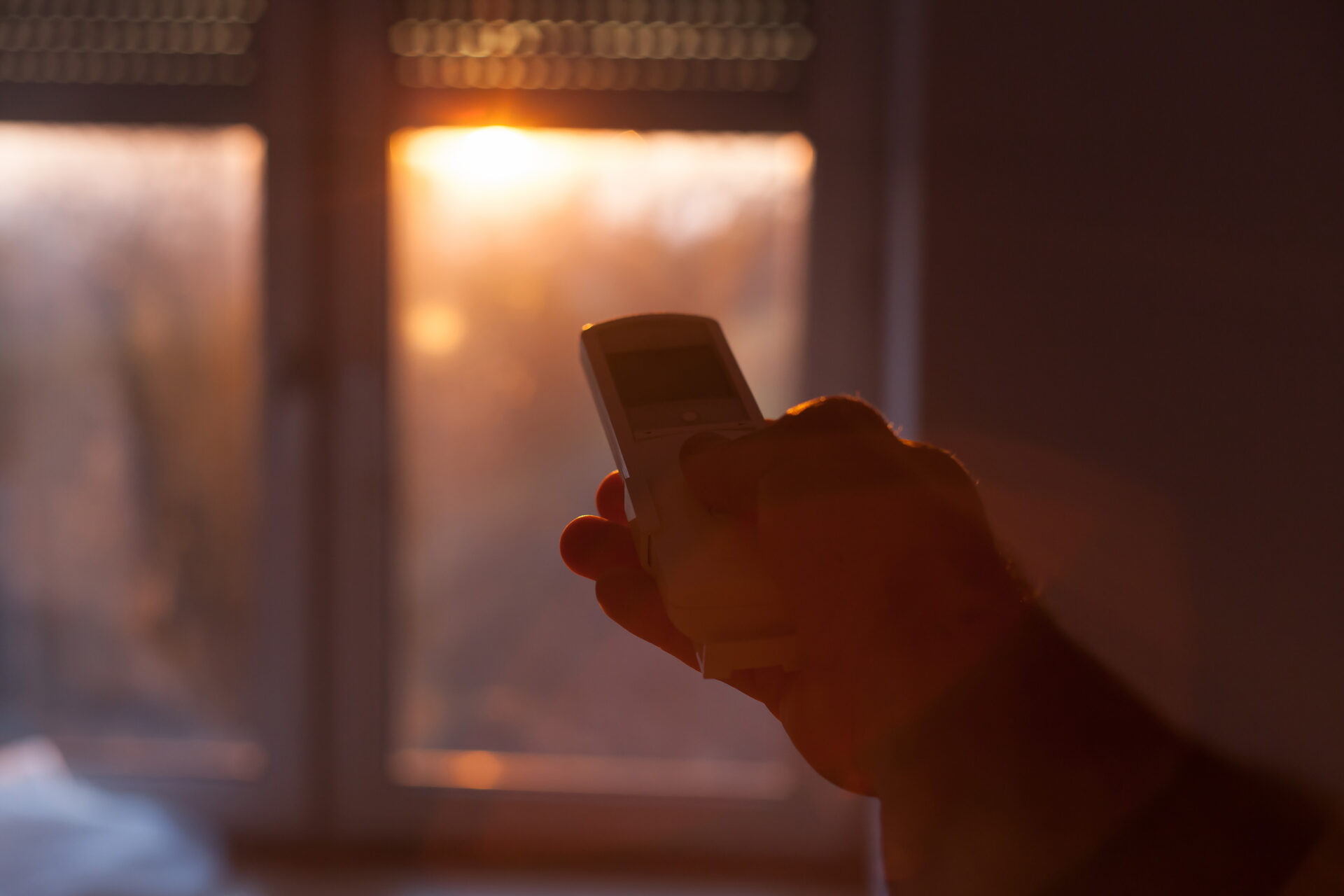 Motorized window blinds in a home with the sunset in the background.