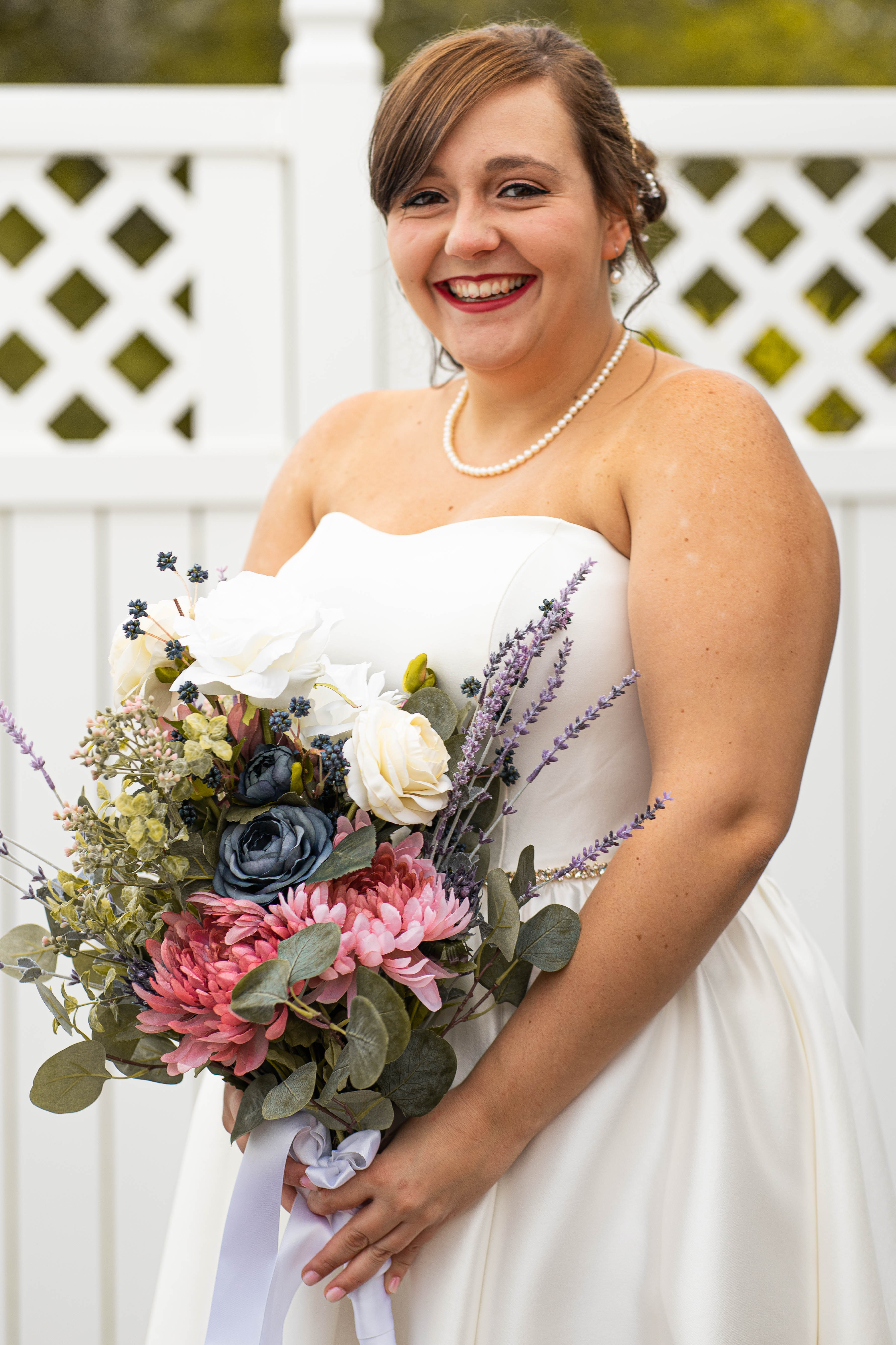 A vibrant bridal bouquet featuring a mix of red, pink, and purple flowers.