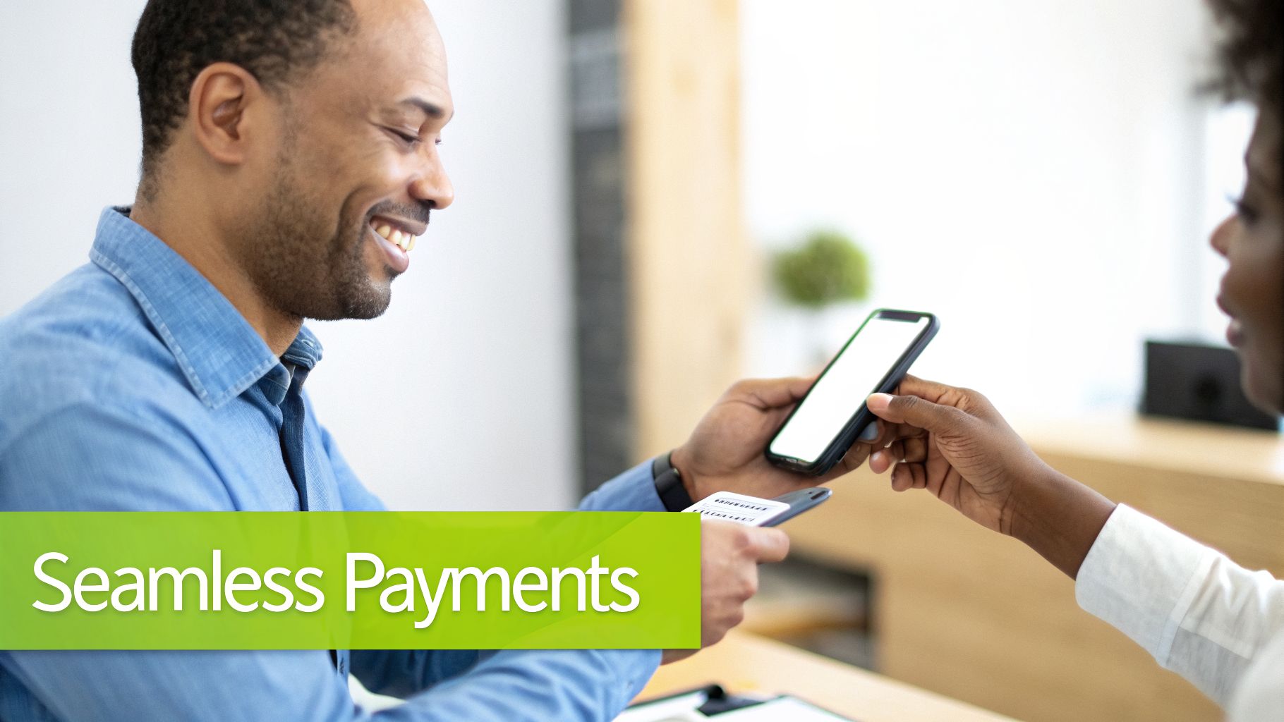 A smiling man processes a contactless payment from a woman's smartphone using a card reader.