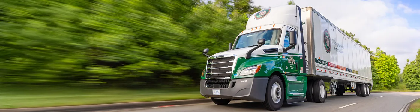 white and orange box truck parked near bare trees during daytime