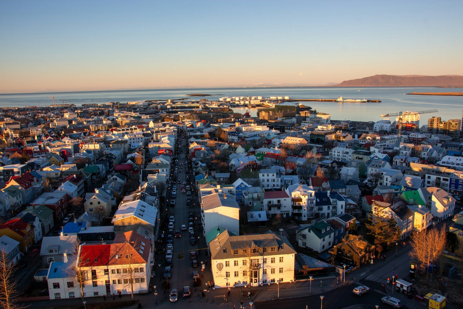Aerial view of downtown Reykjavik, Iceland, with colorful rooftops, Faxaflói Bay, and Mount Esja in the distance.