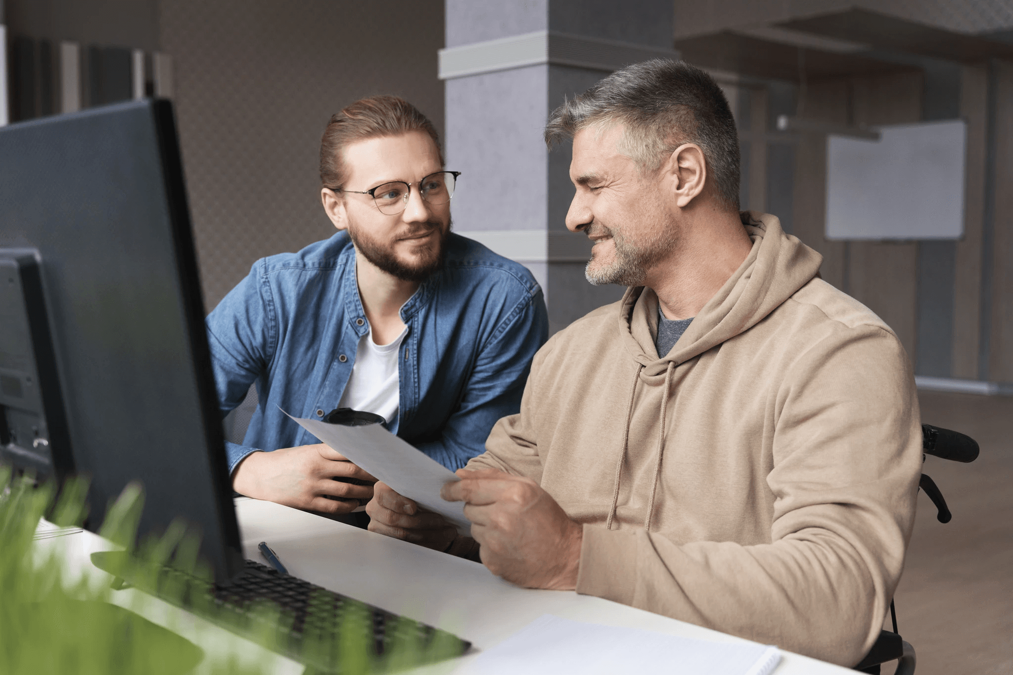 A winding road cuts through rocky terrain, surrounded by patches of green grass and illuminated by sunlight.