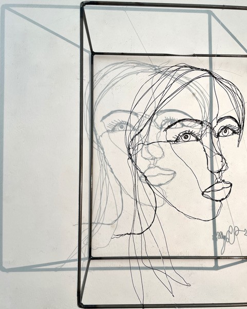 Sculpture en fil de fer représentant le visage d'une femme dans un cadre en fil de fer, vue détaillée de profil