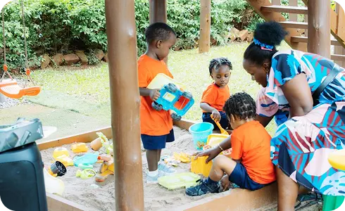 Toddler exploring creative learning materials under teacher supervision