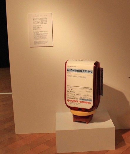 installation view of a drug bottle on a short piedestal