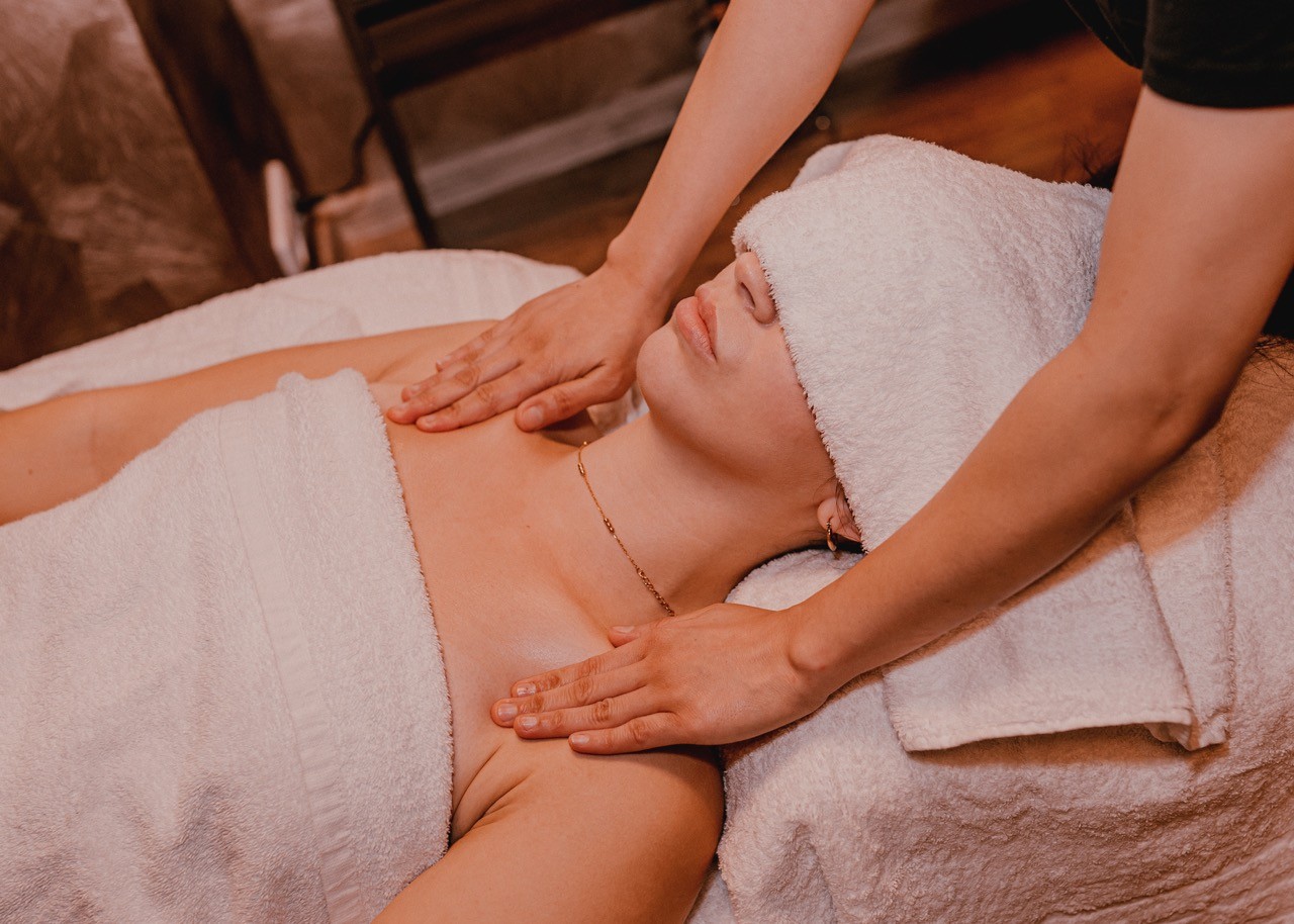 Detailní pohled na ruce thajské masérky provádějící tradiční masáž šíjí v salonu LAYA Spa Ritual