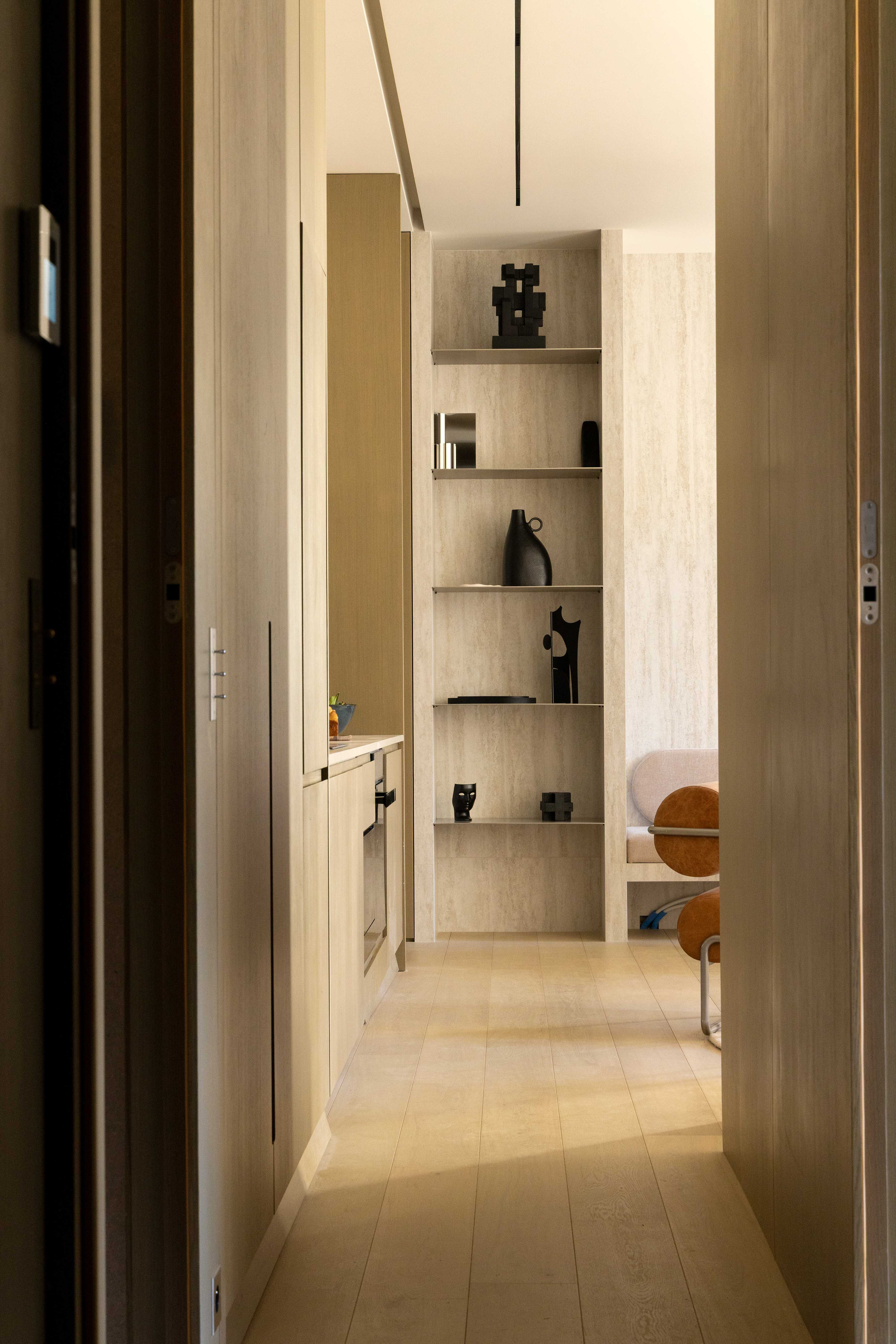 Couloir d'entree en bois clair avec etagere de niches decoratives, objets design noirs et parquet naturel