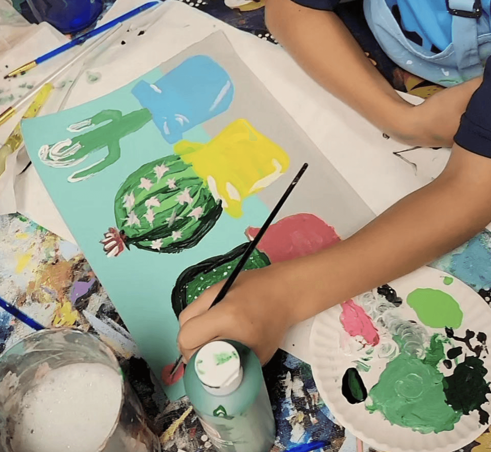 a close up of a child painting three cacti