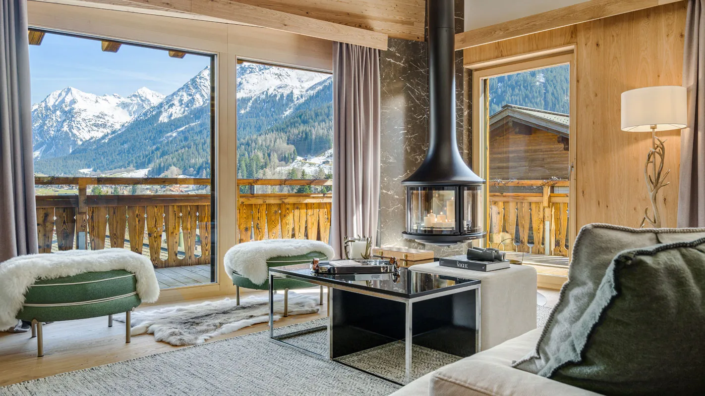Silvretta Klosters living room with suspended fireplace, alpine wood interiors, and panoramic Swiss Alps views