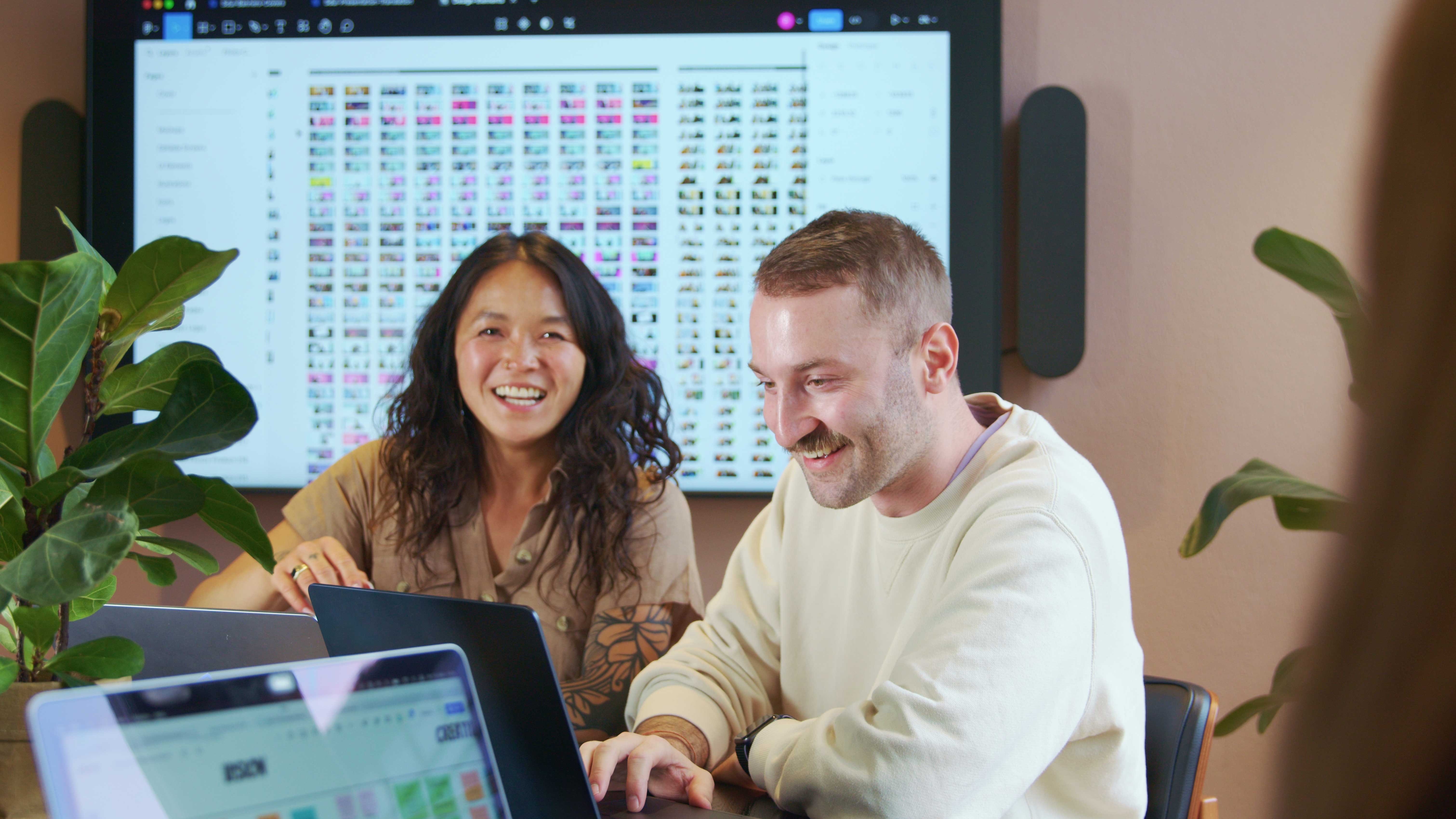 Team collaboration in modern office space with laptops and digital screen.