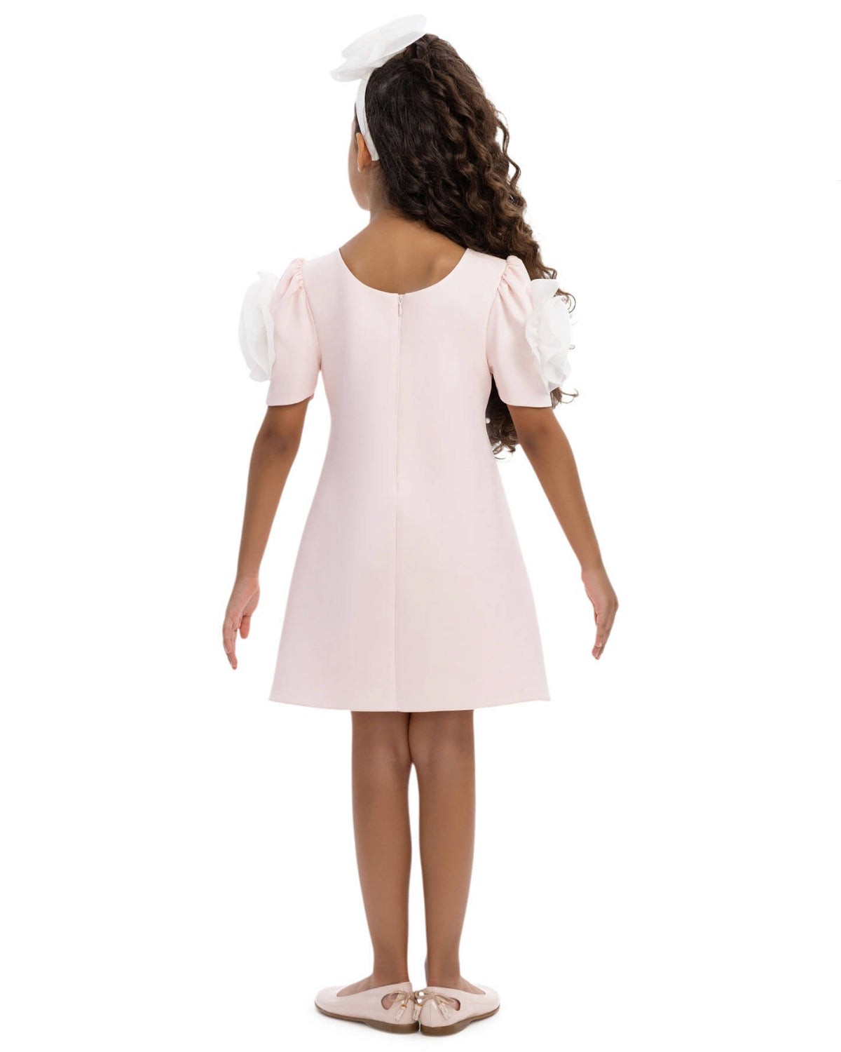 Young girl wearing a white dress with puff sleeves on a white background