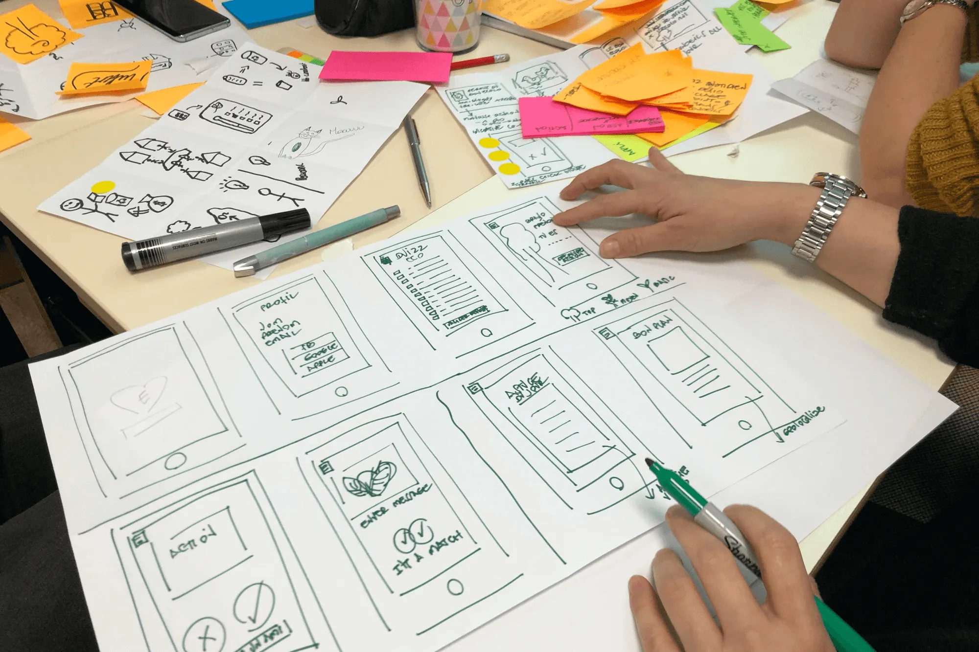 Team sketching app wireframes on paper