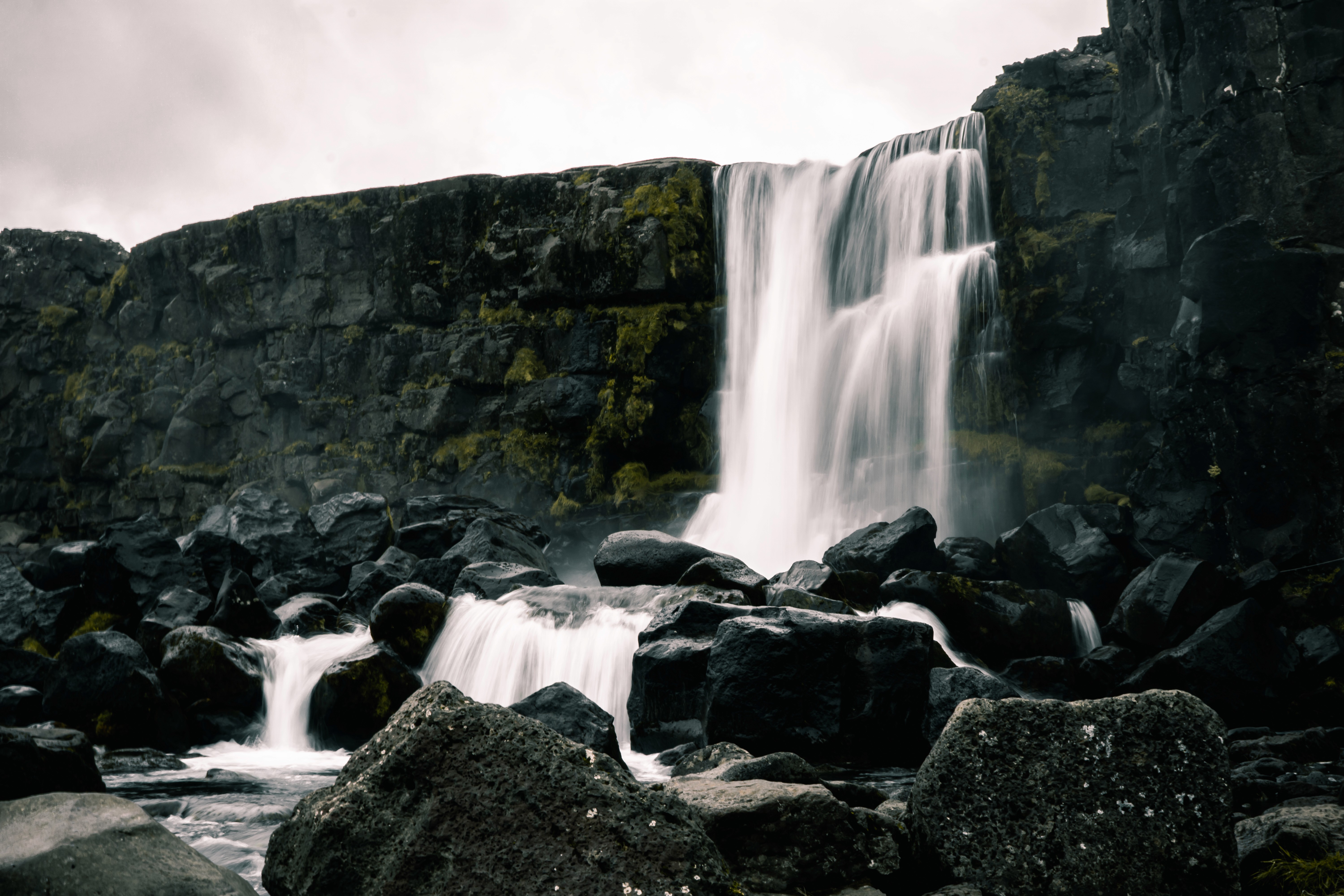 Silhouette of a filmmaker with a camera on a tripod in a dimly lit alley, bathed in orange light and mist, creating a moody, cinematic atmosphere.