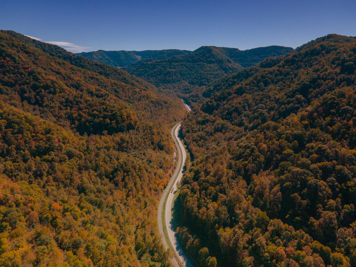 Aerial view of a two-lane mountain road running through an Appalachian valley in fall color