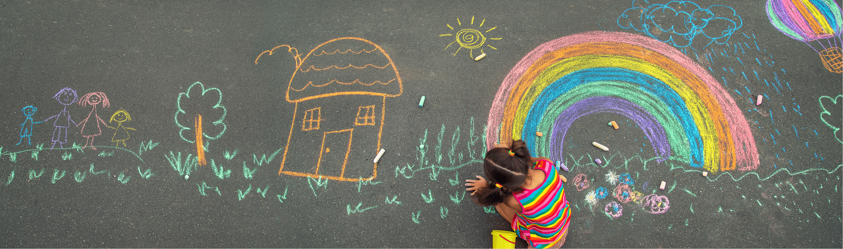 Image of a child drawing a colorful rainbow with chalk on the ground for a non-profit awareness video.