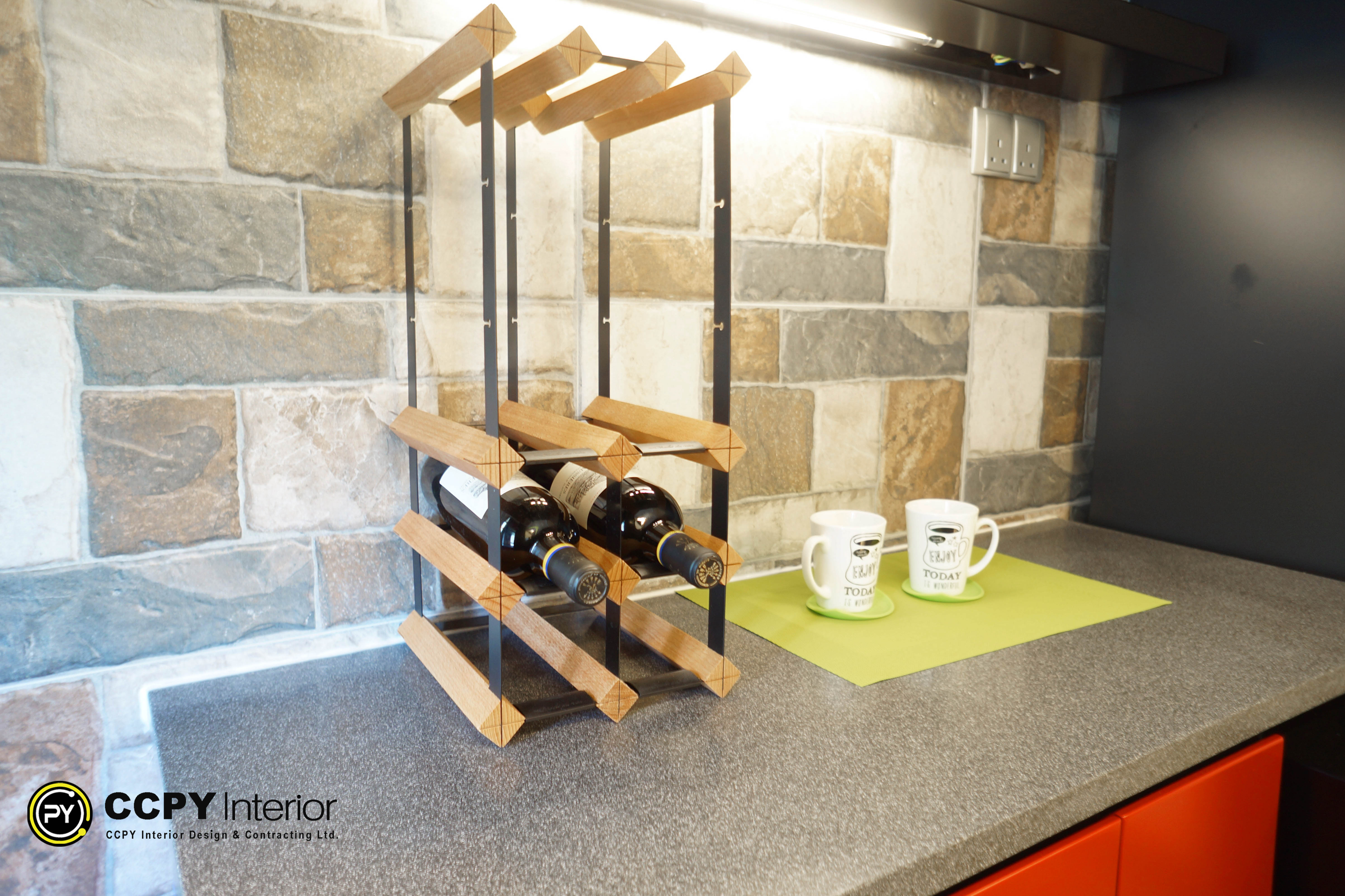 The selected region highlights a modern countertop wine rack positioned on a kitchen workspace kitchen island counter.Design and FeaturesMaterial Structure: Built using a geometric grid frame that combines stained wood strips with black powder-coated metal struts.Capacity & Orientation: Stacks bottles horizontally to keep the wine corks moist, preventing oxidation.Aesthetic Context: Part of a "Smart Luxury" renovation project, designed to maximize functional surface storage within a compact space.