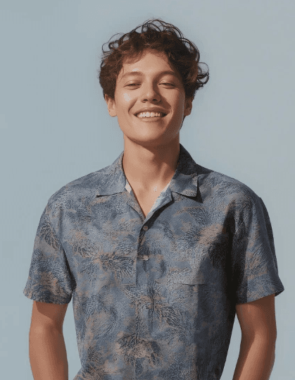 oman in an orange beanie and colorful striped jacket with bold makeup.