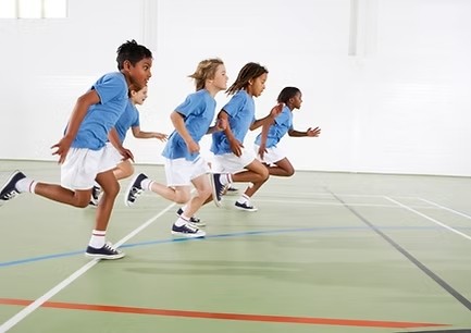 Kinder rennen freudig in einer Sporthalle – Unterstützung für Kinder in Not durch das soziale Engagement der DAG Unternehmensgruppe.