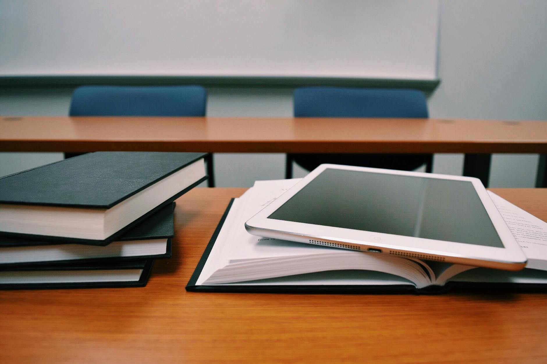 Side-by-side comparison of two tablets displaying different educational software interfaces on a wooden desk.