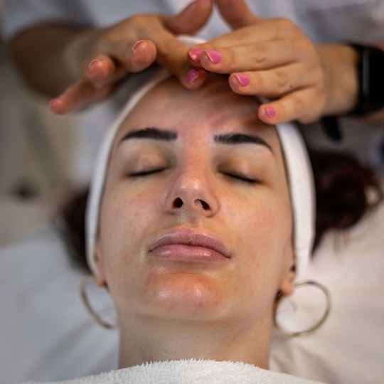One of our dermatologists offering a calming facial to a customer who looks relaxed and refreshed. 