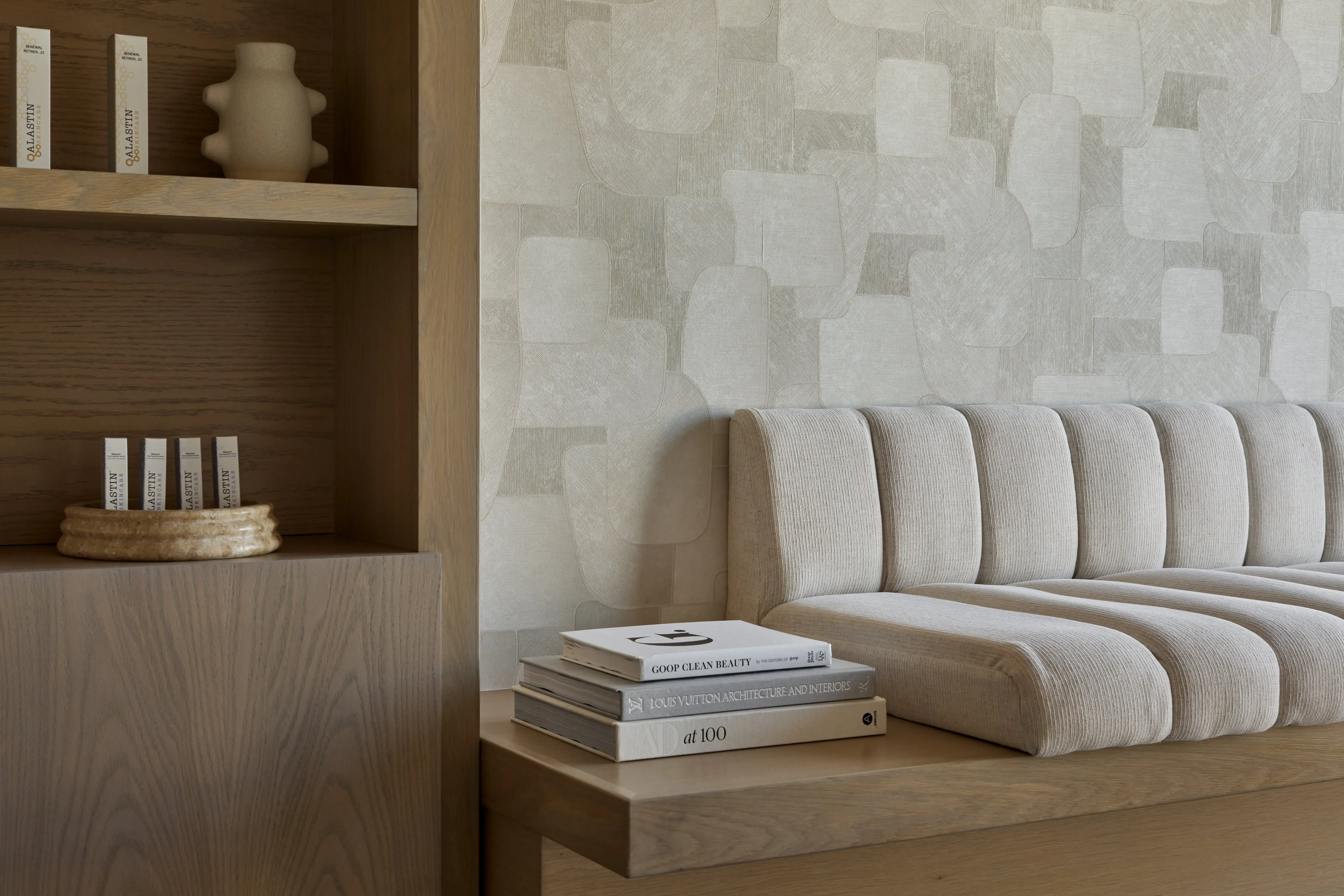 Custom built-in bench seating against a textured neutral feature wall with integrated wood shelving in a wellness studio.