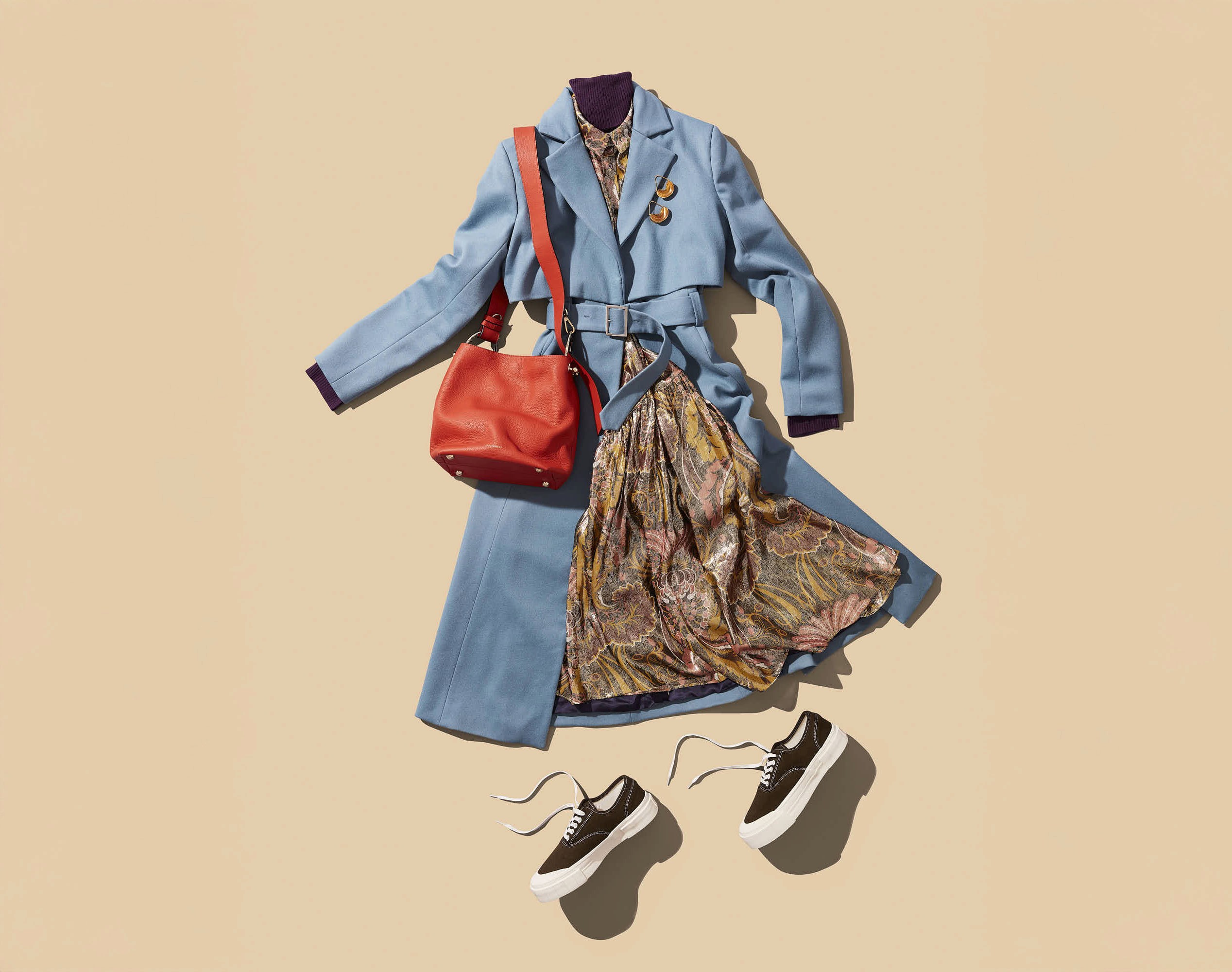 A stylish outfit featuring a blue coat, patterned skirt, red handbag, and stylish shoes on a beige background.