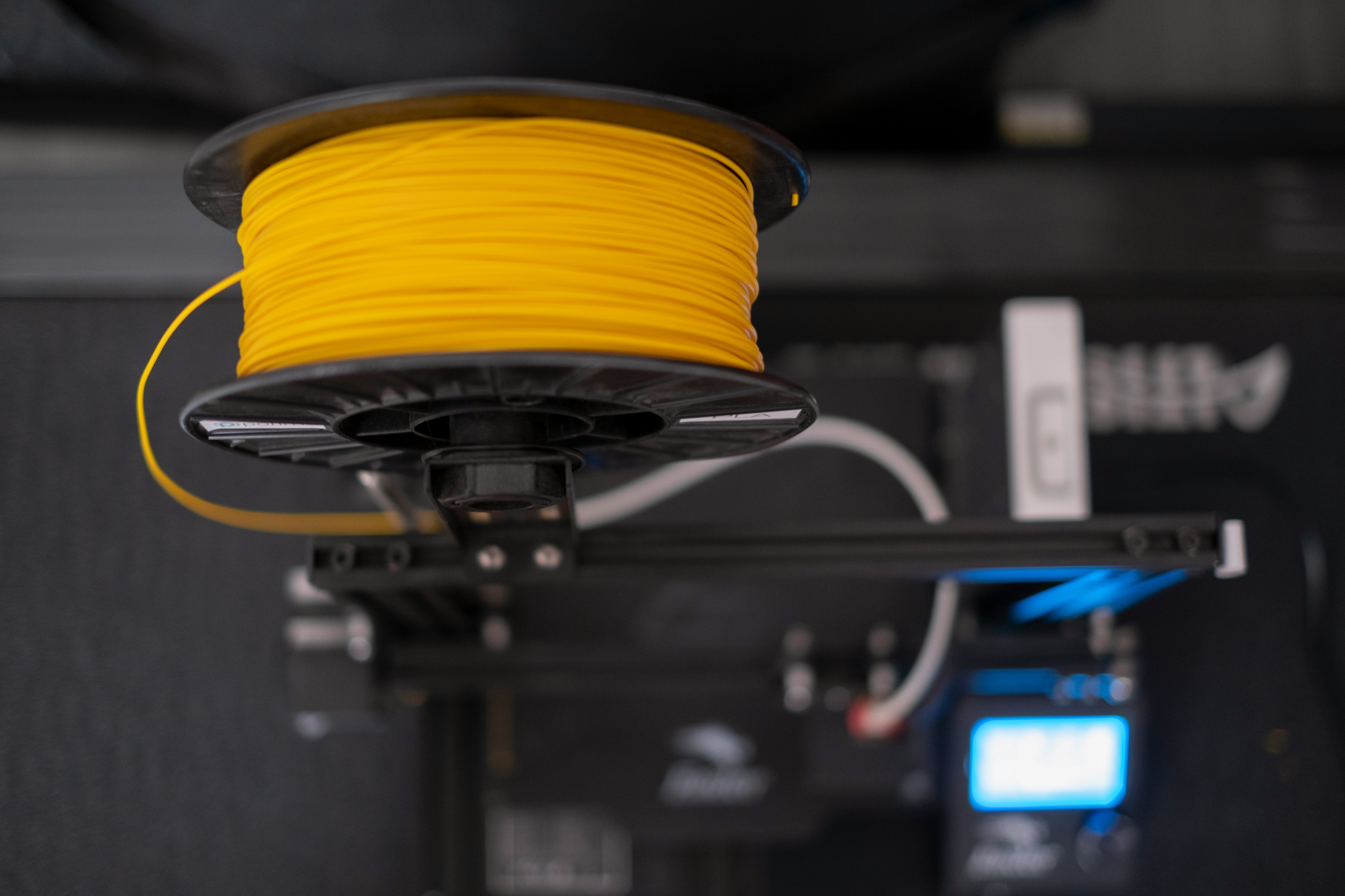 Yellow PLA filament spool mounted on a desktop 3D printer