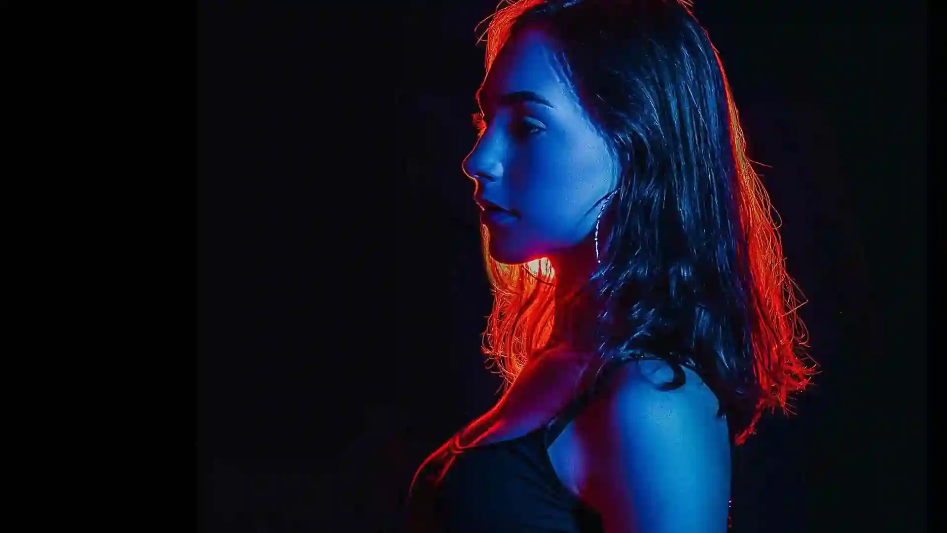 Cinematic profile of a woman in dramatic blue and red neon lighting, representing the premium Aerocity Escorts service.