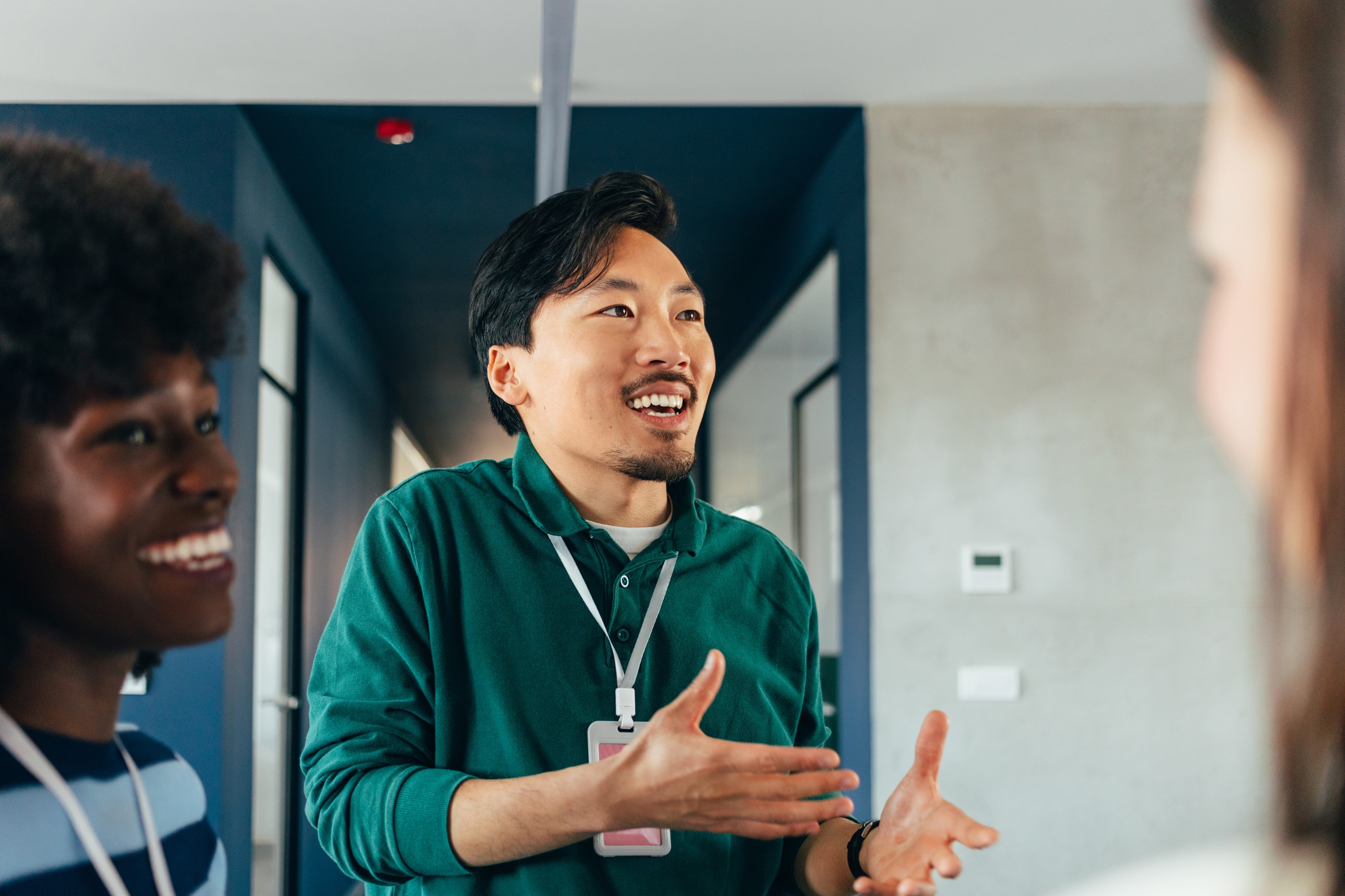 A retirement plan advisor gestures while discussing recordkeeper options with two plan sponsor managers in an office hallway