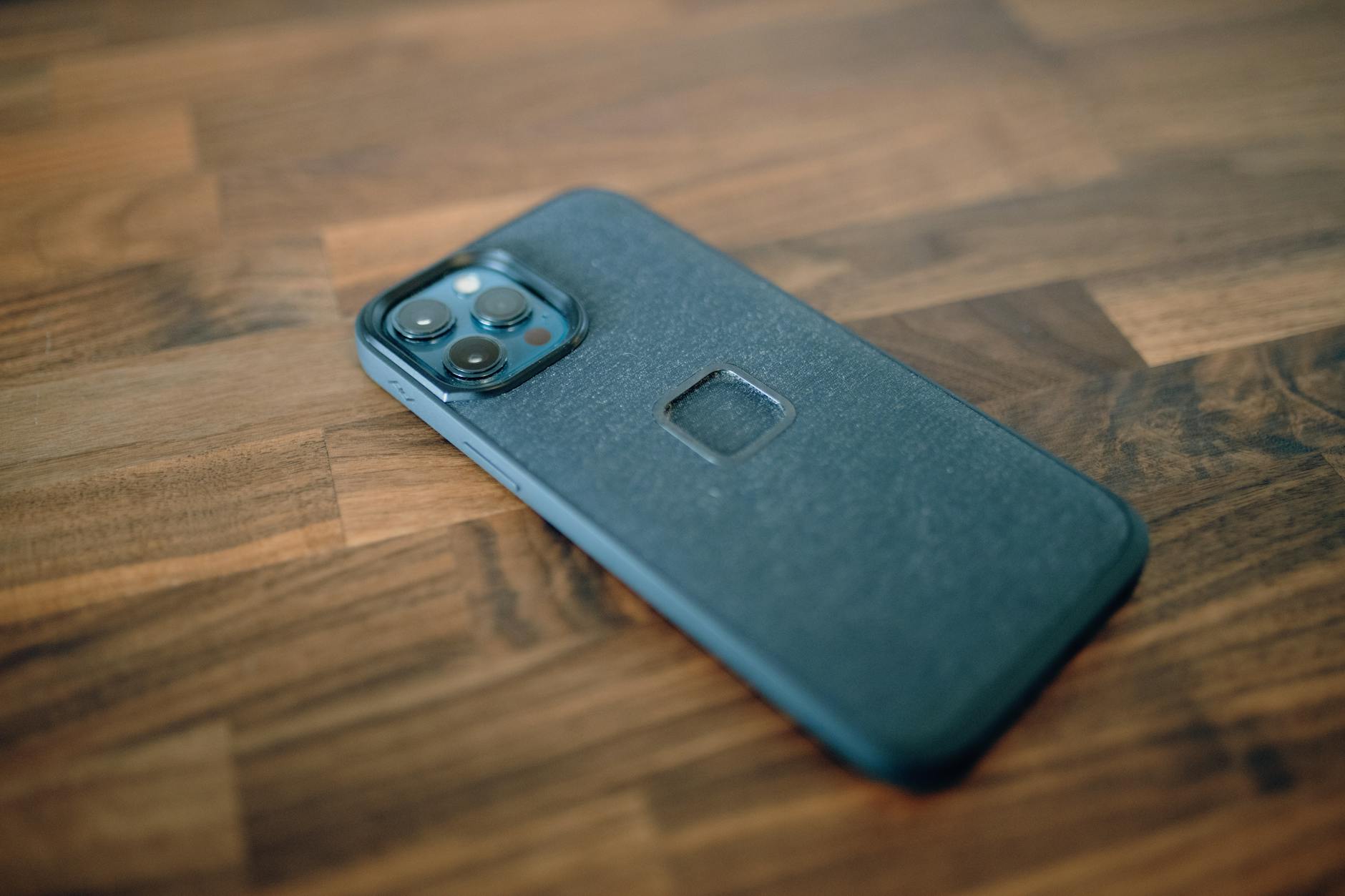 A close-up shot of a smartphone with a protective case, placed on a wooden surface.