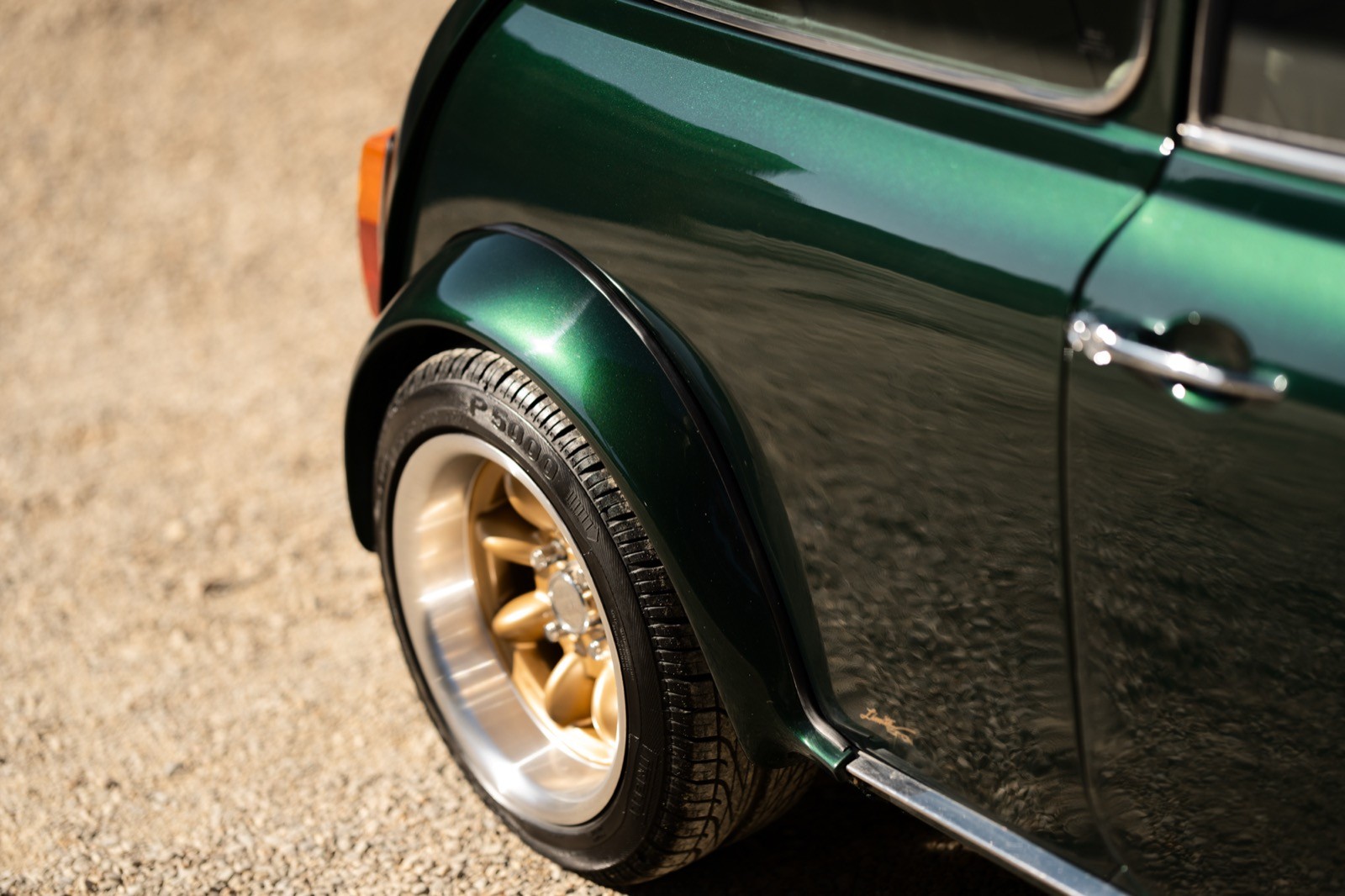A small, green and black vehicle parked on a sandy surface, with a warm sunset lighting the scene.