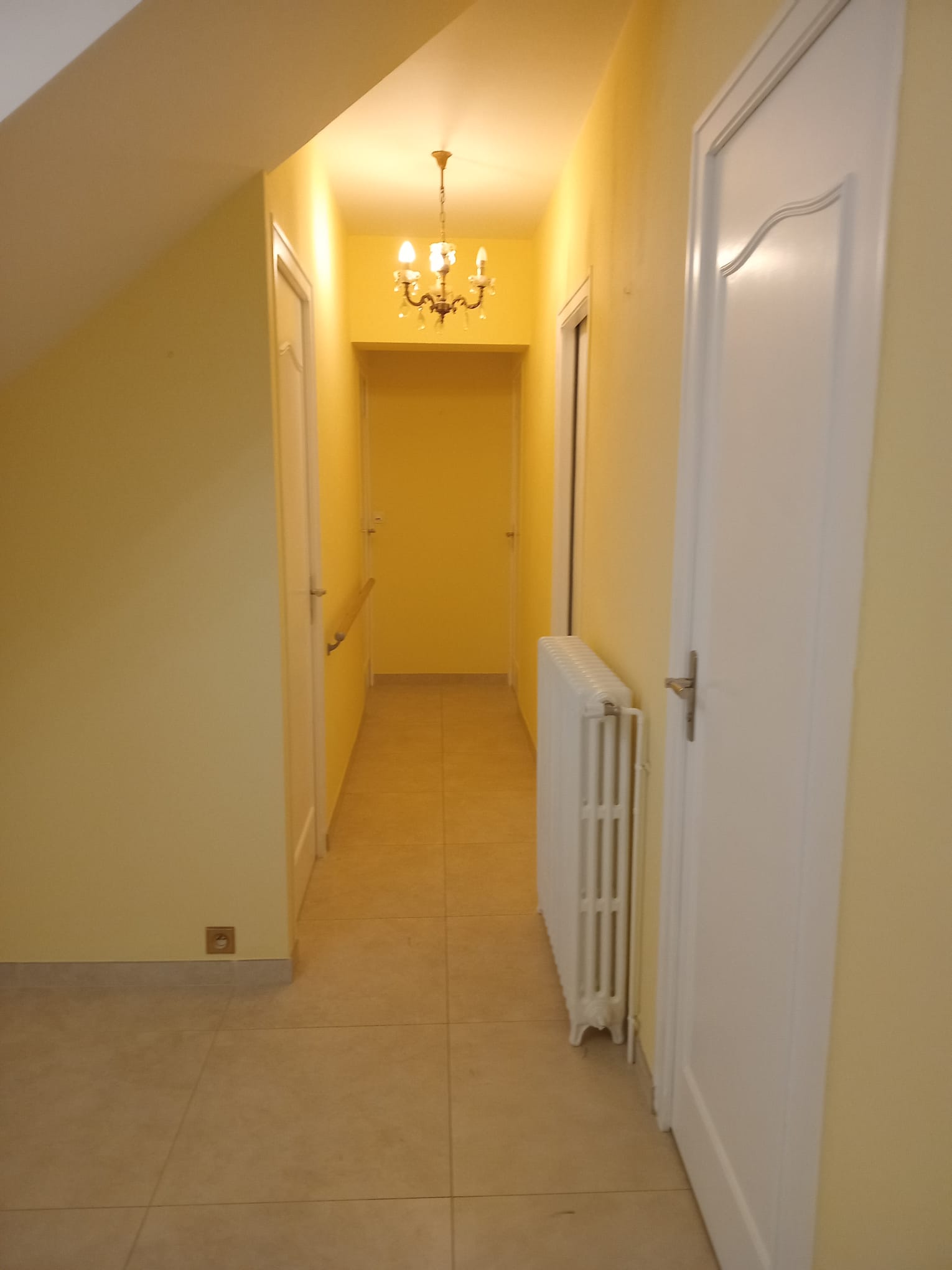 Mur blanc avec une porte en bois et un arbre en premier plan