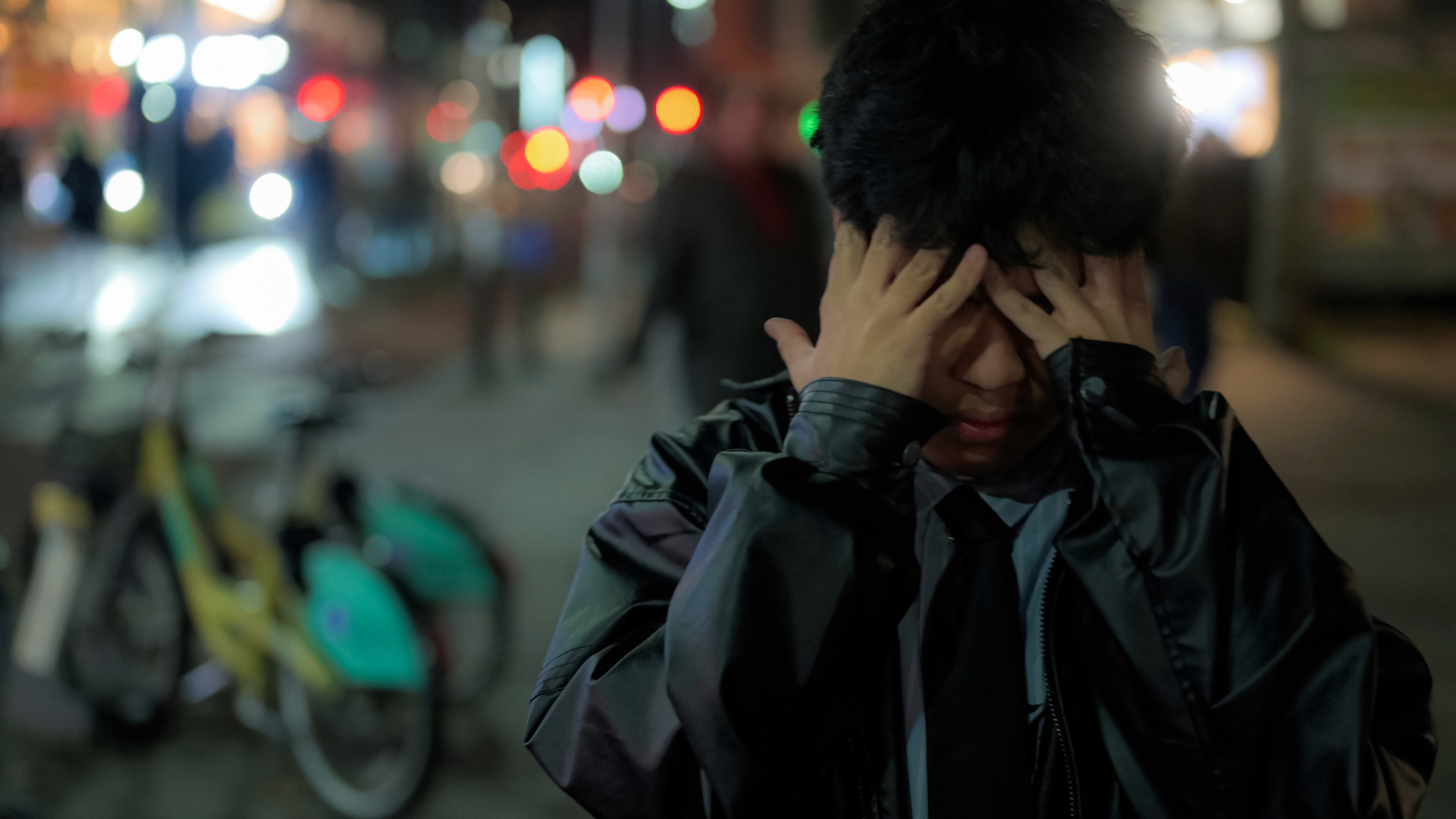 A close-up of a person wearing green-tinted glasses, with a serious expression and smooth skin.