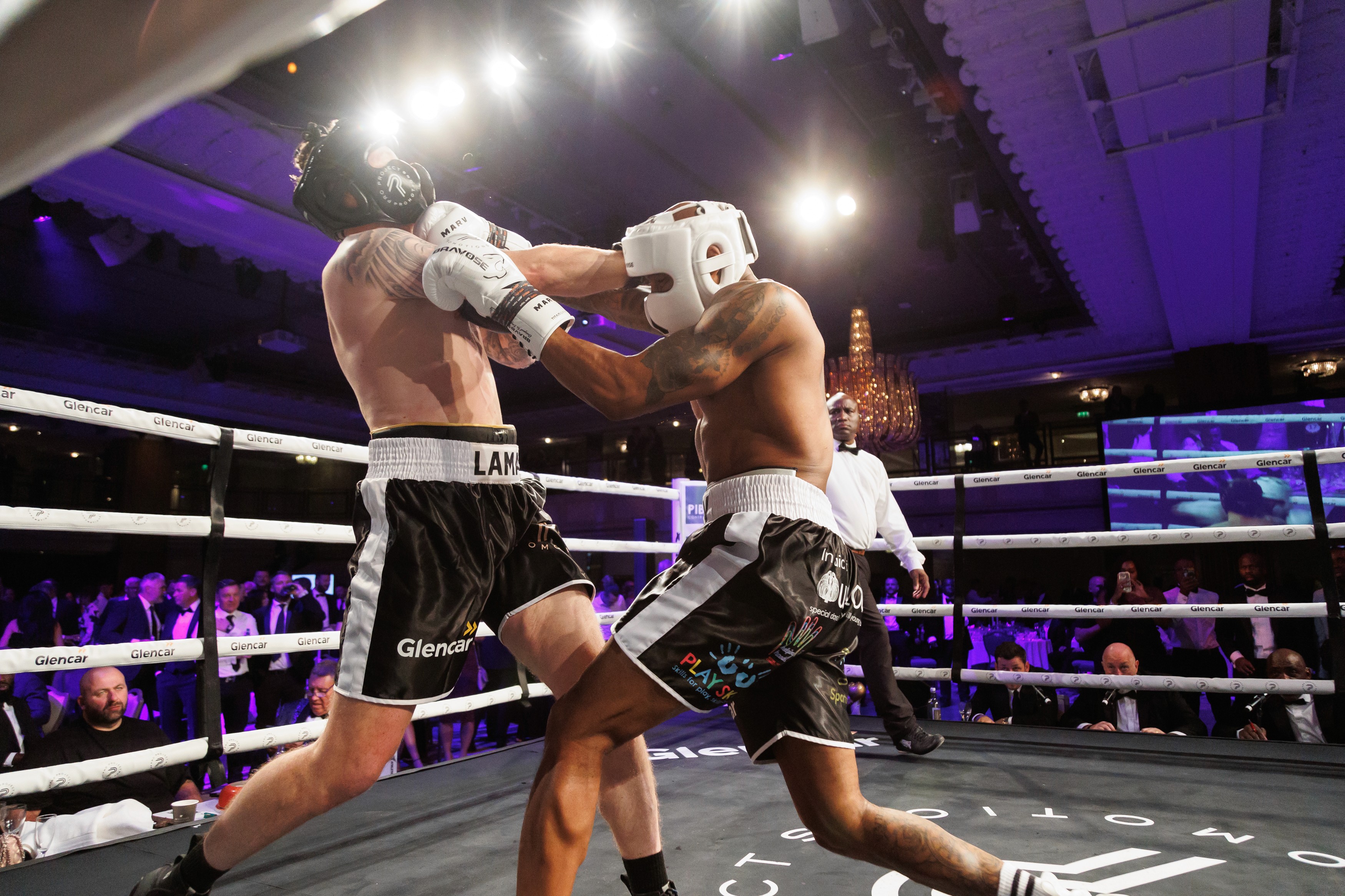 person discussing while standing in front of a large screen in front of people inside dim-lighted room