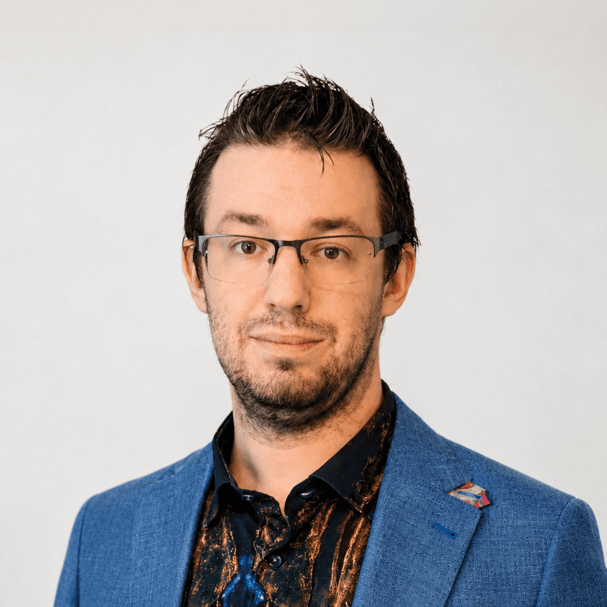 Professional headshot of a MelodyArc team member, a man with glasses and stubble wearing a blue blazer.