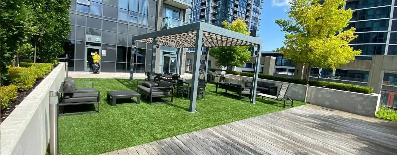 Urban rooftop terrace with artificial turf, seating area, and pergola setup by Falcons Landscaping.