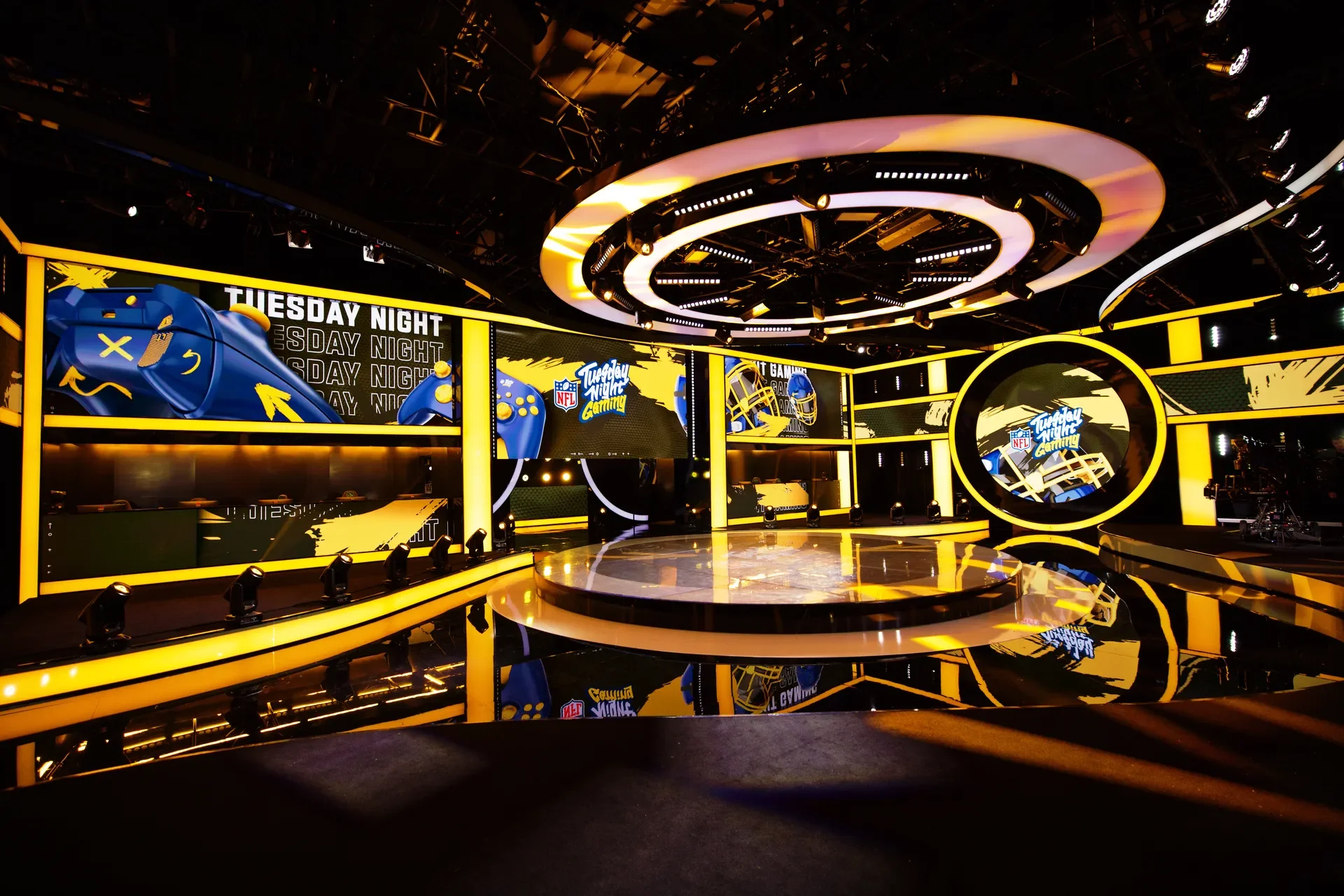 The Tuesday Night Gaming studio lit in yellow, with the show's name on the screens