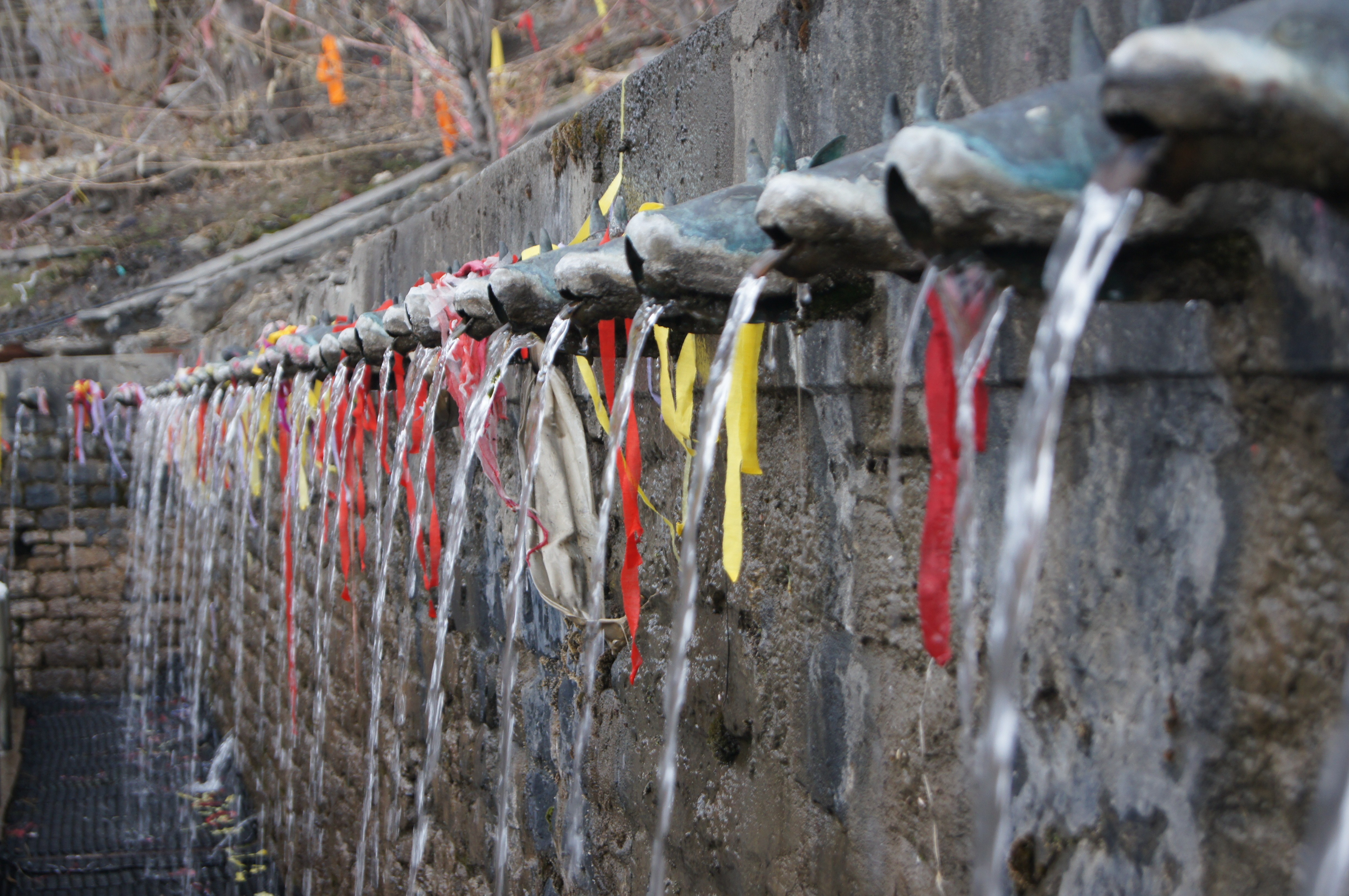 people walking on beach near brown concrete building under white clouds and blue sky during daytime