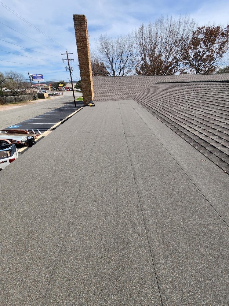 Crossed hip roof with architectural shingles on a church in Marble Falls, complemented by a modified bitumen flat porch for a functional and enduring design.