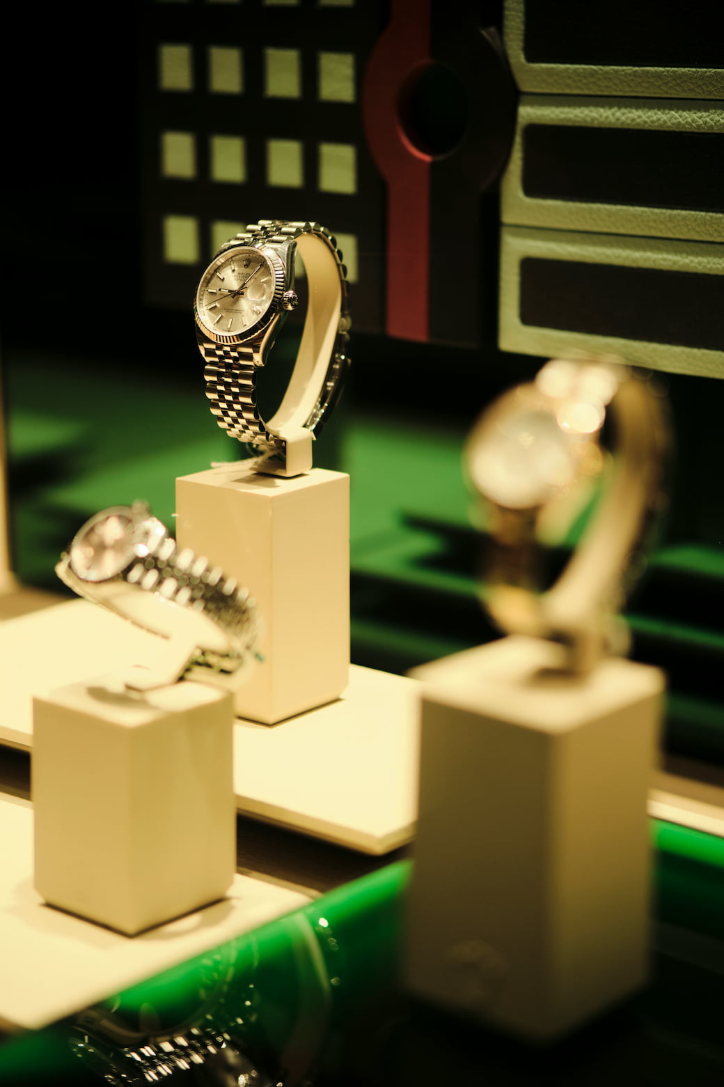 Three luxury watches displayed on stands