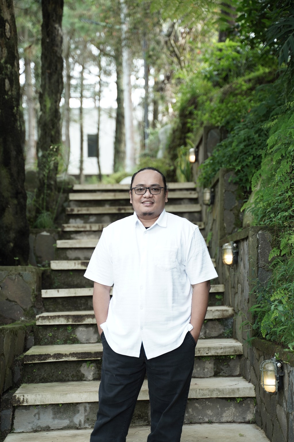 A winding road cuts through rocky terrain, surrounded by patches of green grass and illuminated by sunlight.