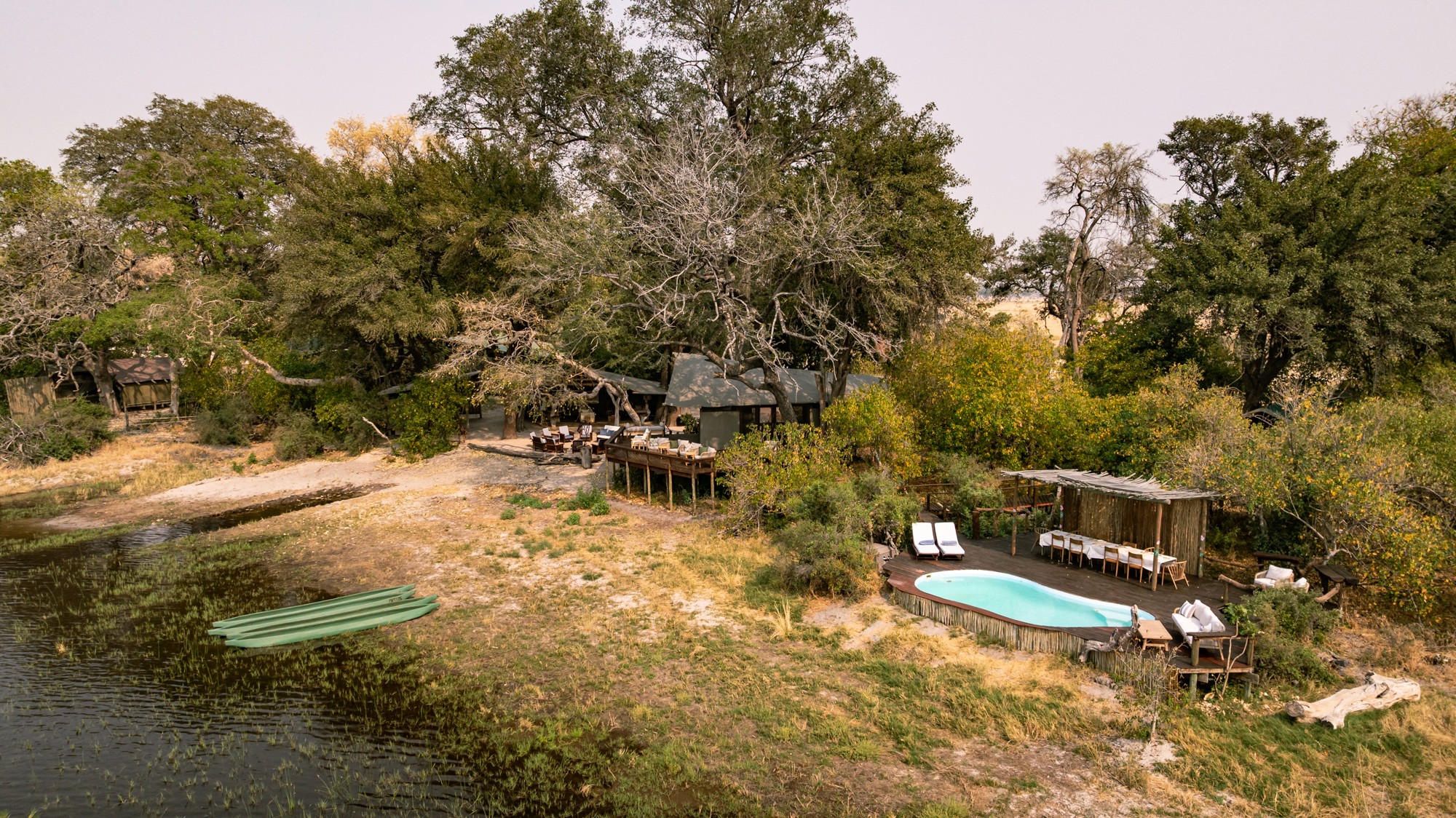 Kujwana Delta Ride, Okavango Delta, Botswana. Drönarvy över Kujwana Camp, pool och pooldäck samt mokoros i flodkanten.