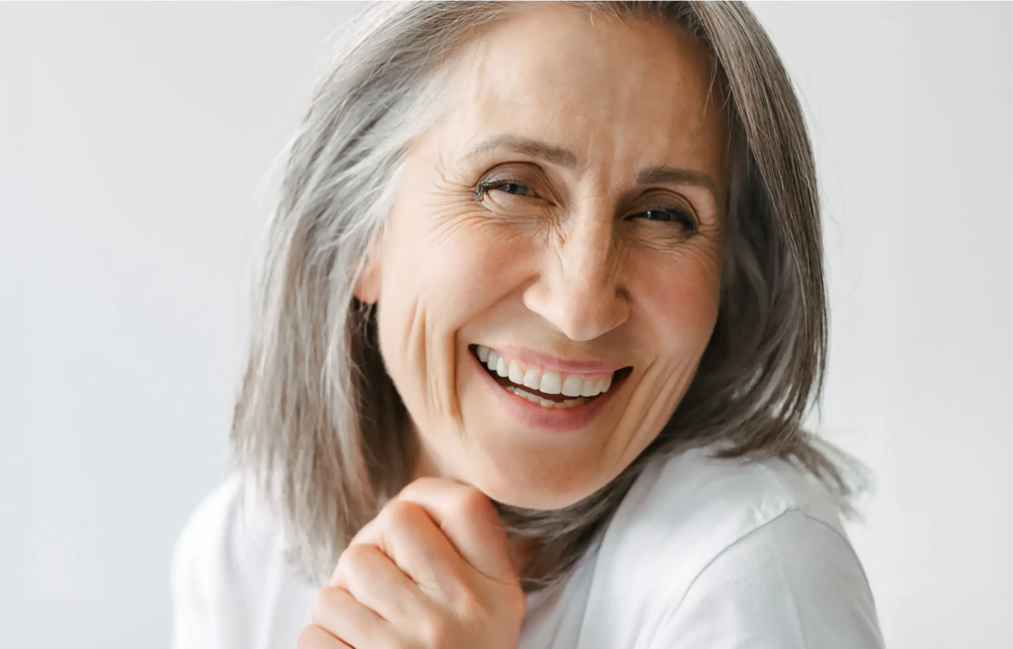 Kobieta z uśmiechem prezentująca efekty bondingu na swoich zębach.