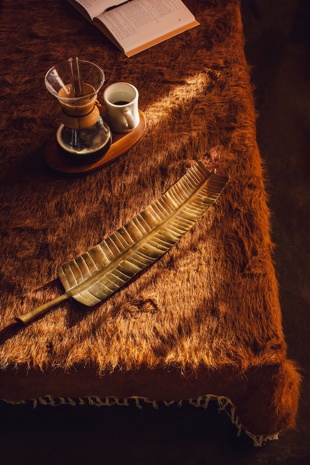The coffee table in the lobby at Particle Studio holds a book, a decoritive metal leaf tray, and a fresh pot of coffee.
