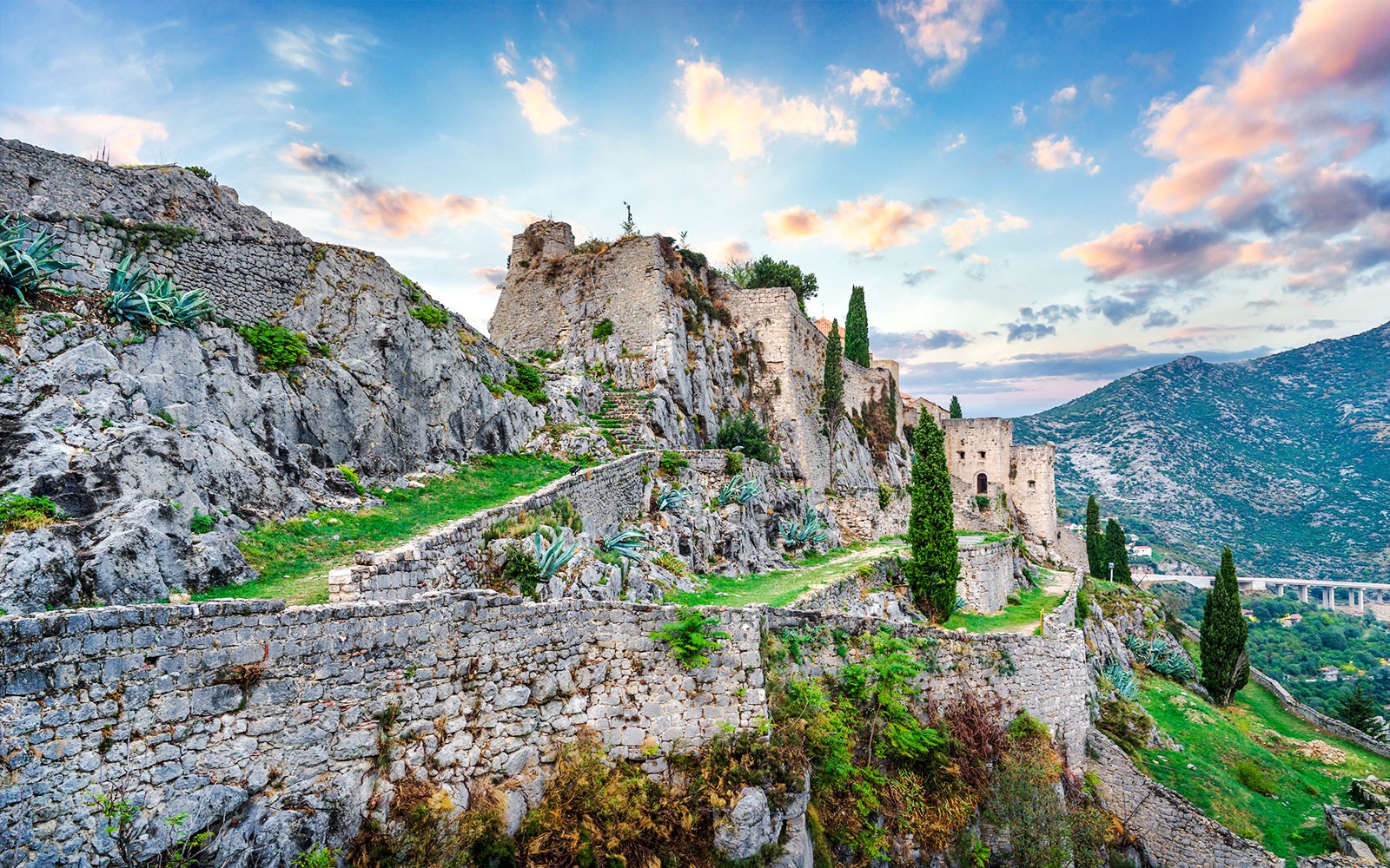 Fortezza di Klis su una collina rocciosa con mura di pietra e vegetazione vicino a Spalato, Croazia.