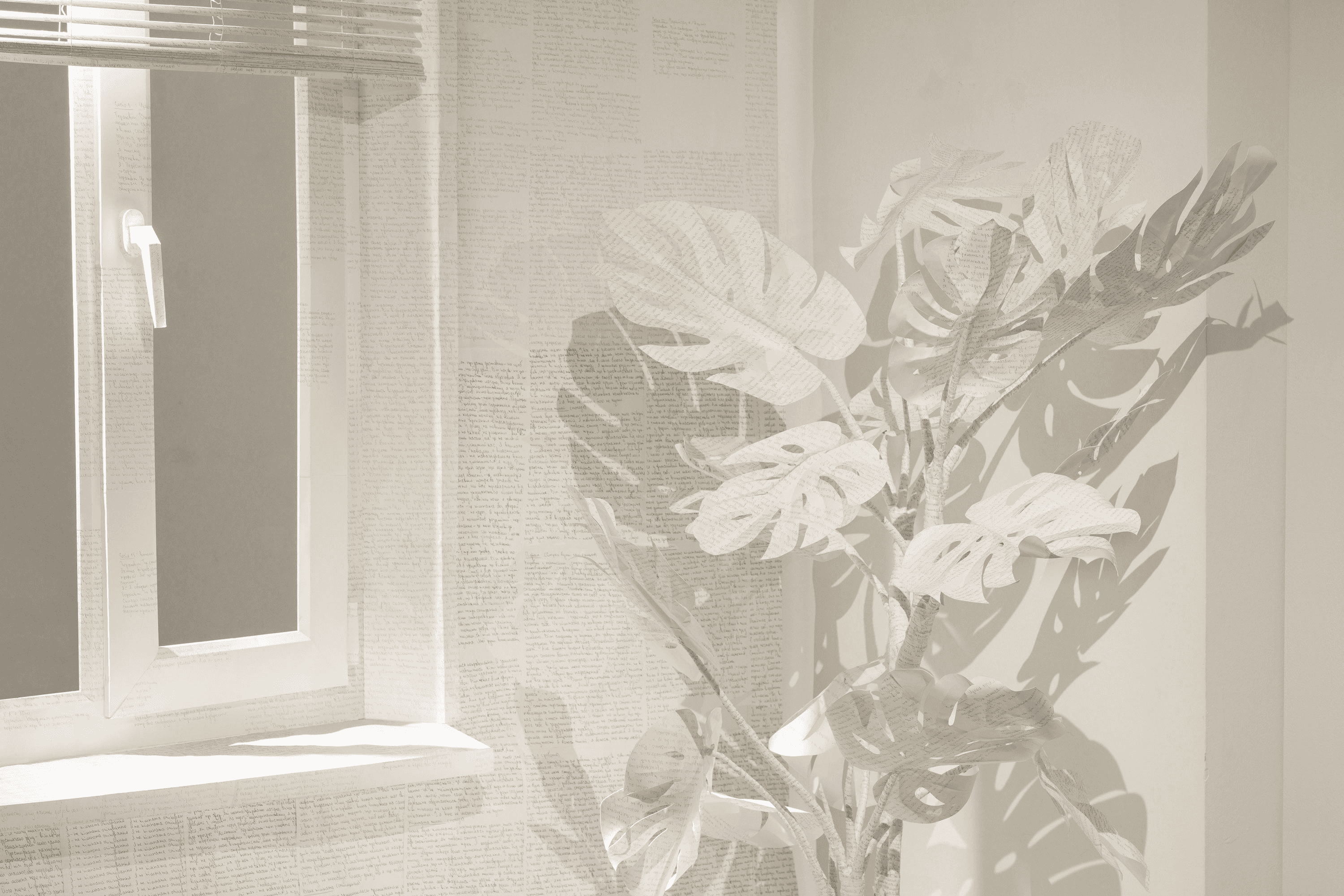 White paper plant with broad cut leaves covered in handwritten text, positioned beside a window and text-covered wall.
