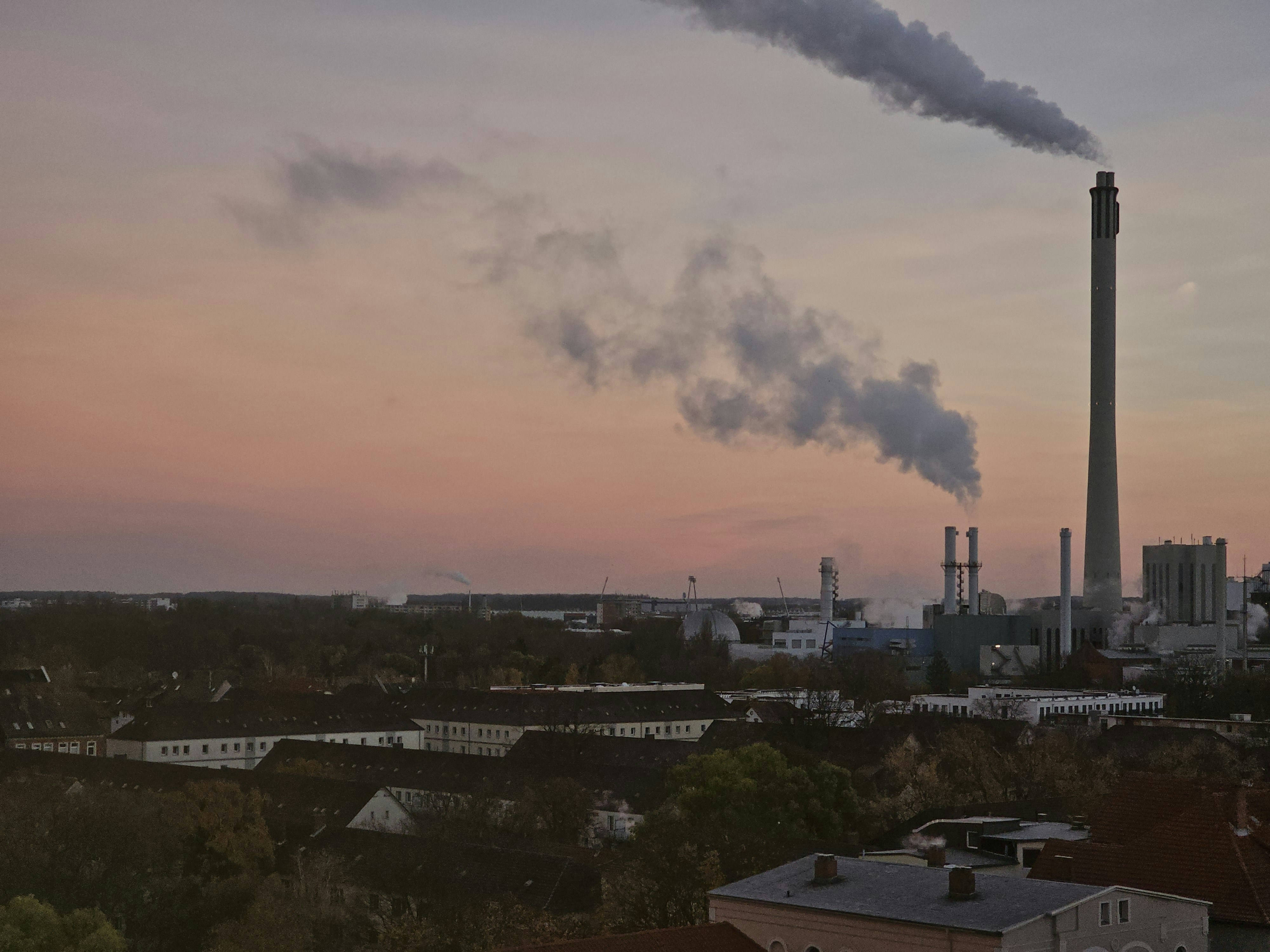 a smokestack emits from a factory at sunset