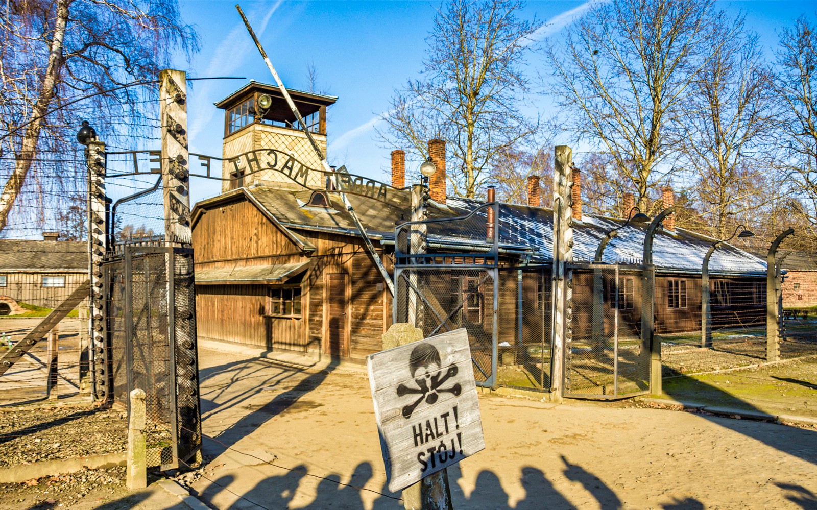 Puerta de entrada a Auschwitz-Birkenau con cartel de advertencia, parte de un recorrido de día completo.