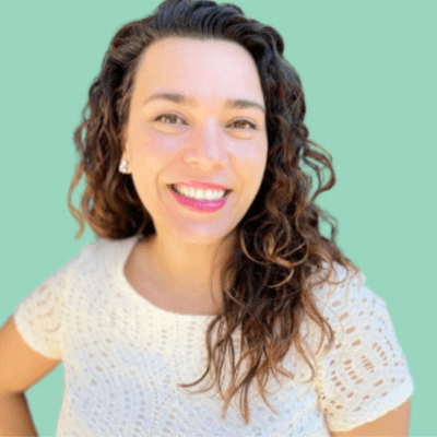 Portrait of Andrea Hickson, founder and executive director of NICU Alumni, smiling at the camera against a soft green background, wearing a white textured top.