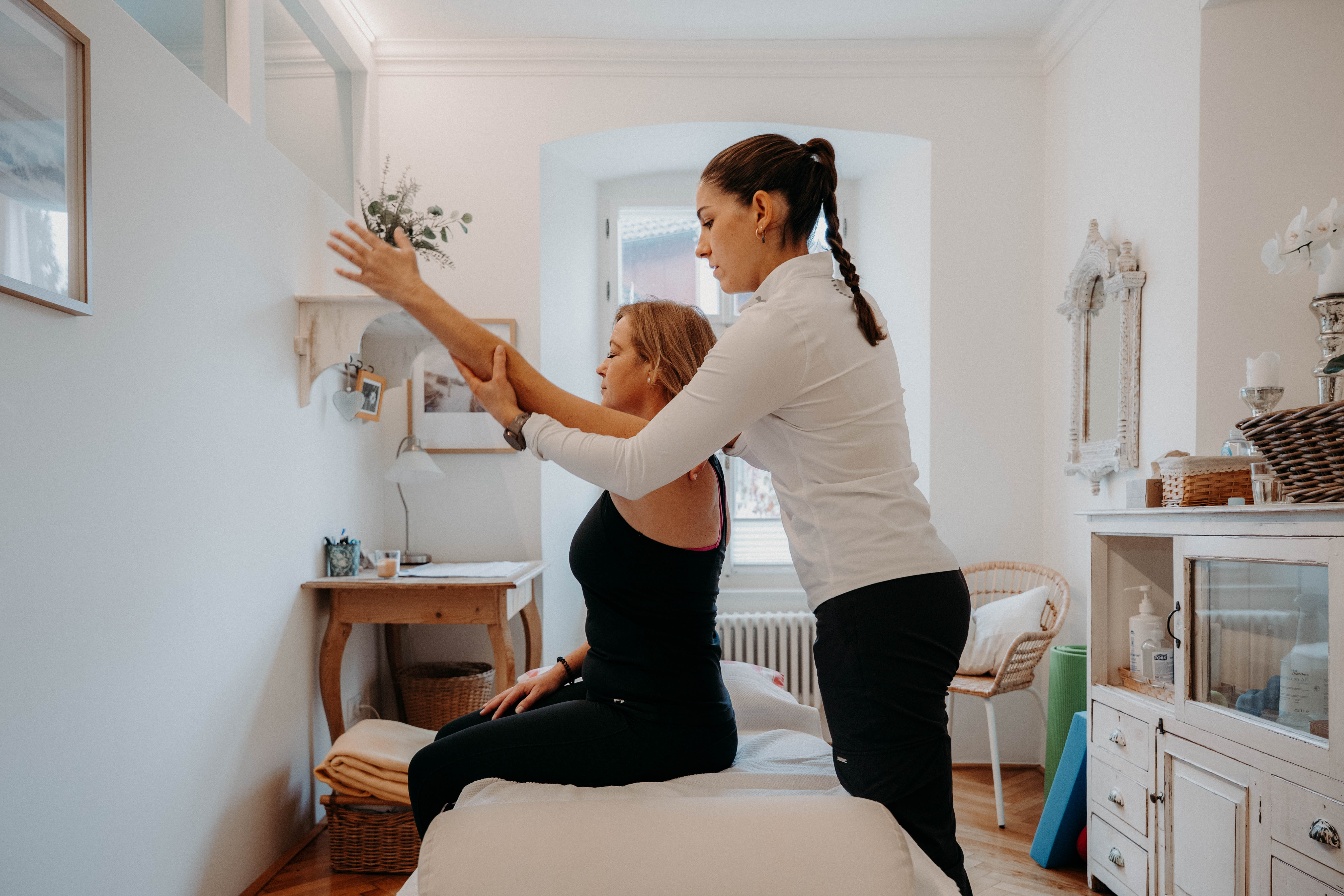 Physiotherapeutin hilft Patientin bei Armübung auf Liege. Therapie, Rehabilitation, Gesundheit, Beweglichkeit.